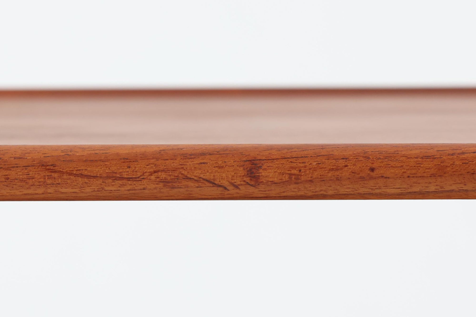 北欧より買い付けた、Hans J. WegnerによるAT10です。天板にはチーク無垢材が使われ、脚部にはオーク無垢材が採用されています。経年変化した籐の棚が特徴的で、温かみのある雰囲気を醸し出します。幅160cmというサイズ感は、3Pソファの前面に並べて使用すると、程良い距離感を保ちながら使いやすく、空間全体のバランスを整えます。縁が削り出されて丸みを帯びたデザインは、AT10の特徴であり、その独特の魅力が感じられます。天板裏面にはAndreas Tuck社の刻印がございます。