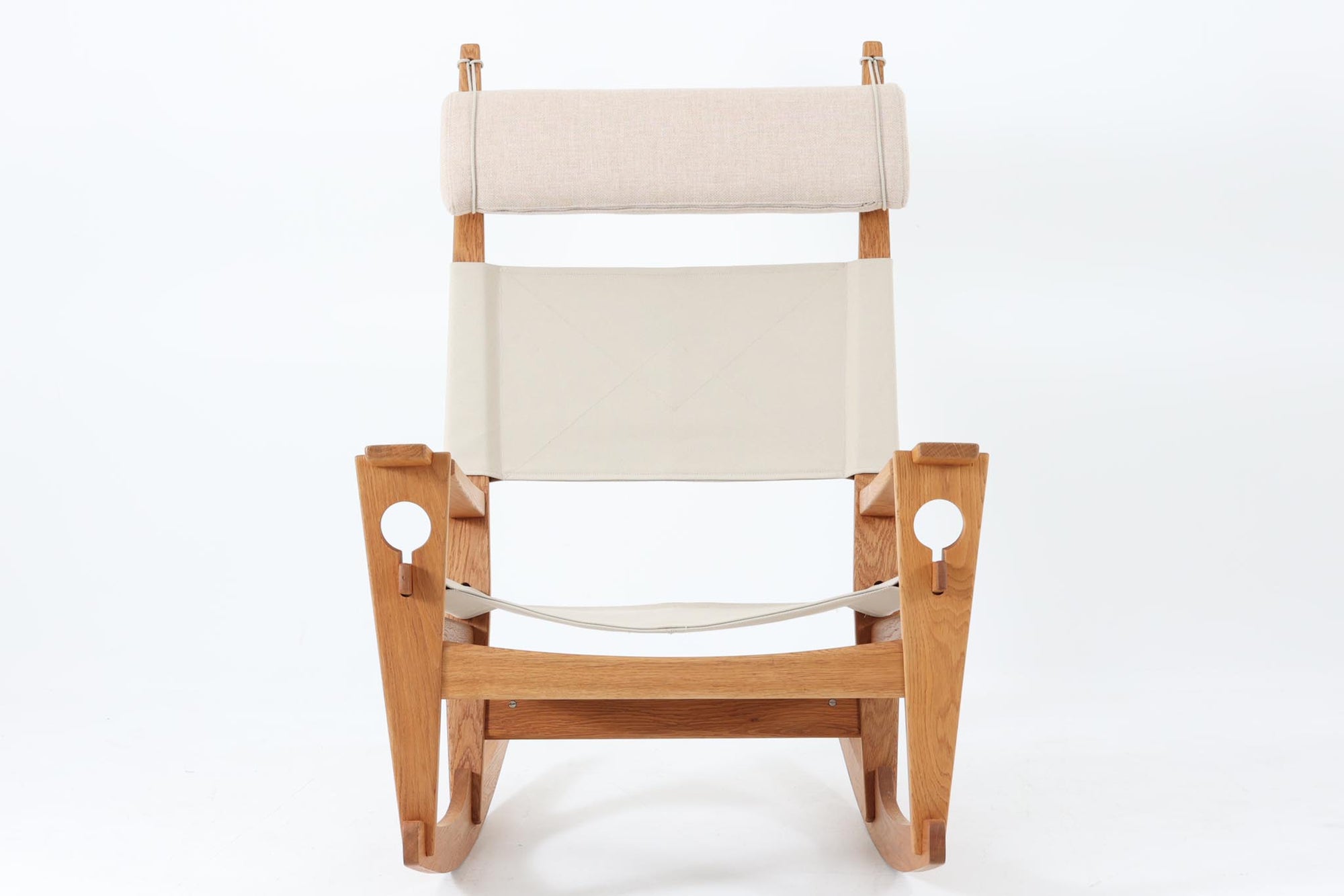 Hans J. Wegnerが1967年にデザインしたロッキングチェア「キーホールチェア（GE673）」は、GETAmA社製の一脚です。特徴的な「鍵穴」のような形状の座面固定方法が名前の由来で、左右のアーム下に引っ掛けた2本の棒が座面を支える構造です。帆布製の背もたれと座面は、ハンモックのような座り心地を提供し、まるで包み込まれるような安心感を感じさせます。ロッキングチェアならではの揺れと、程よい可動領域が特徴で、家の中でゆったりとくつろぐのに最適です。座面は簡単に取り外せ、クリーニングにも配慮されています。軽量で機能性とデザインが見事に調和した、ウェグナーならではの作品です。