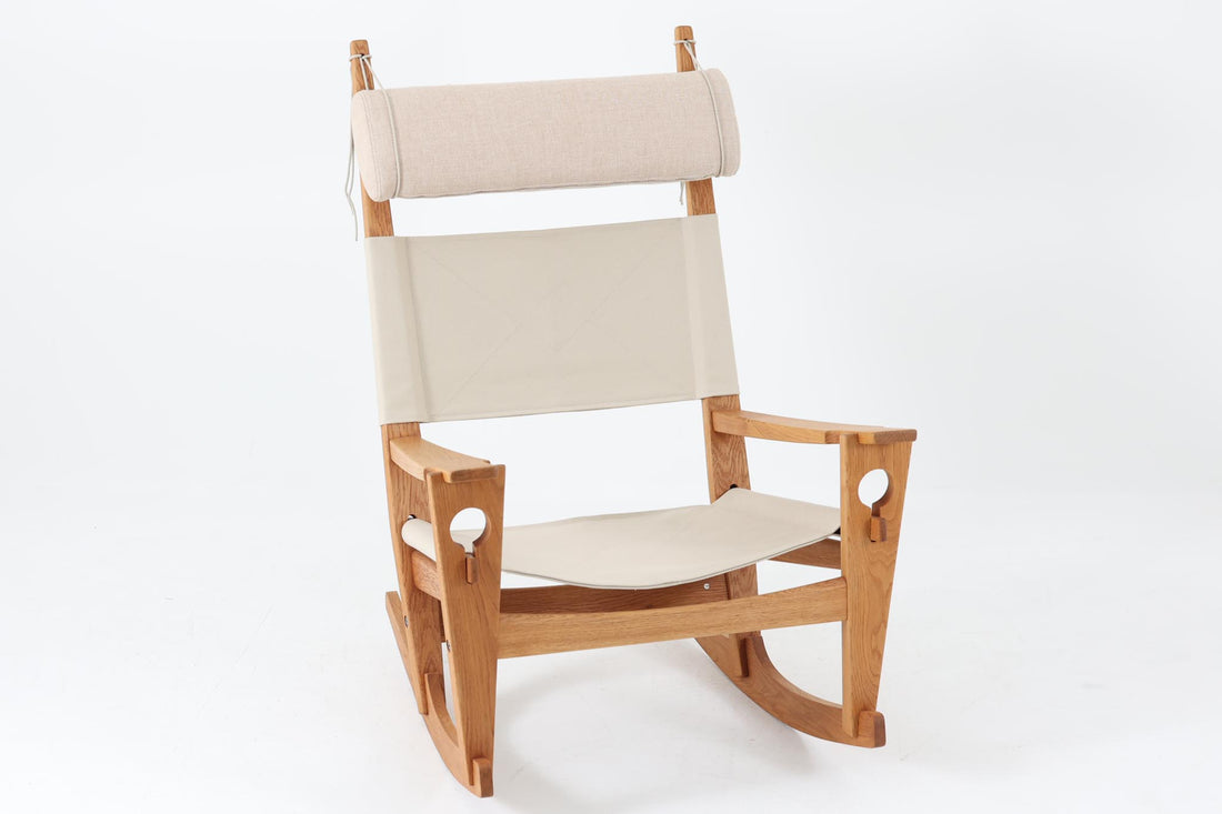 Hans J. Wegnerが1967年にデザインしたロッキングチェア「キーホールチェア（GE673）」は、GETAmA社製の一脚です。特徴的な「鍵穴」のような形状の座面固定方法が名前の由来で、左右のアーム下に引っ掛けた2本の棒が座面を支える構造です。帆布製の背もたれと座面は、ハンモックのような座り心地を提供し、まるで包み込まれるような安心感を感じさせます。ロッキングチェアならではの揺れと、程よい可動領域が特徴で、家の中でゆったりとくつろぐのに最適です。座面は簡単に取り外せ、クリーニングにも配慮されています。軽量で機能性とデザインが見事に調和した、ウェグナーならではの作品です。