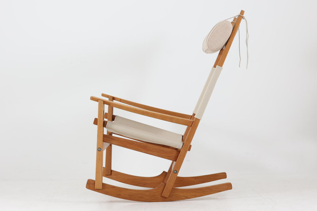 Hans J. Wegnerが1967年にデザインしたロッキングチェア「キーホールチェア（GE673）」は、GETAmA社製の一脚です。特徴的な「鍵穴」のような形状の座面固定方法が名前の由来で、左右のアーム下に引っ掛けた2本の棒が座面を支える構造です。帆布製の背もたれと座面は、ハンモックのような座り心地を提供し、まるで包み込まれるような安心感を感じさせます。ロッキングチェアならではの揺れと、程よい可動領域が特徴で、家の中でゆったりとくつろぐのに最適です。座面は簡単に取り外せ、クリーニングにも配慮されています。軽量で機能性とデザインが見事に調和した、ウェグナーならではの作品です。