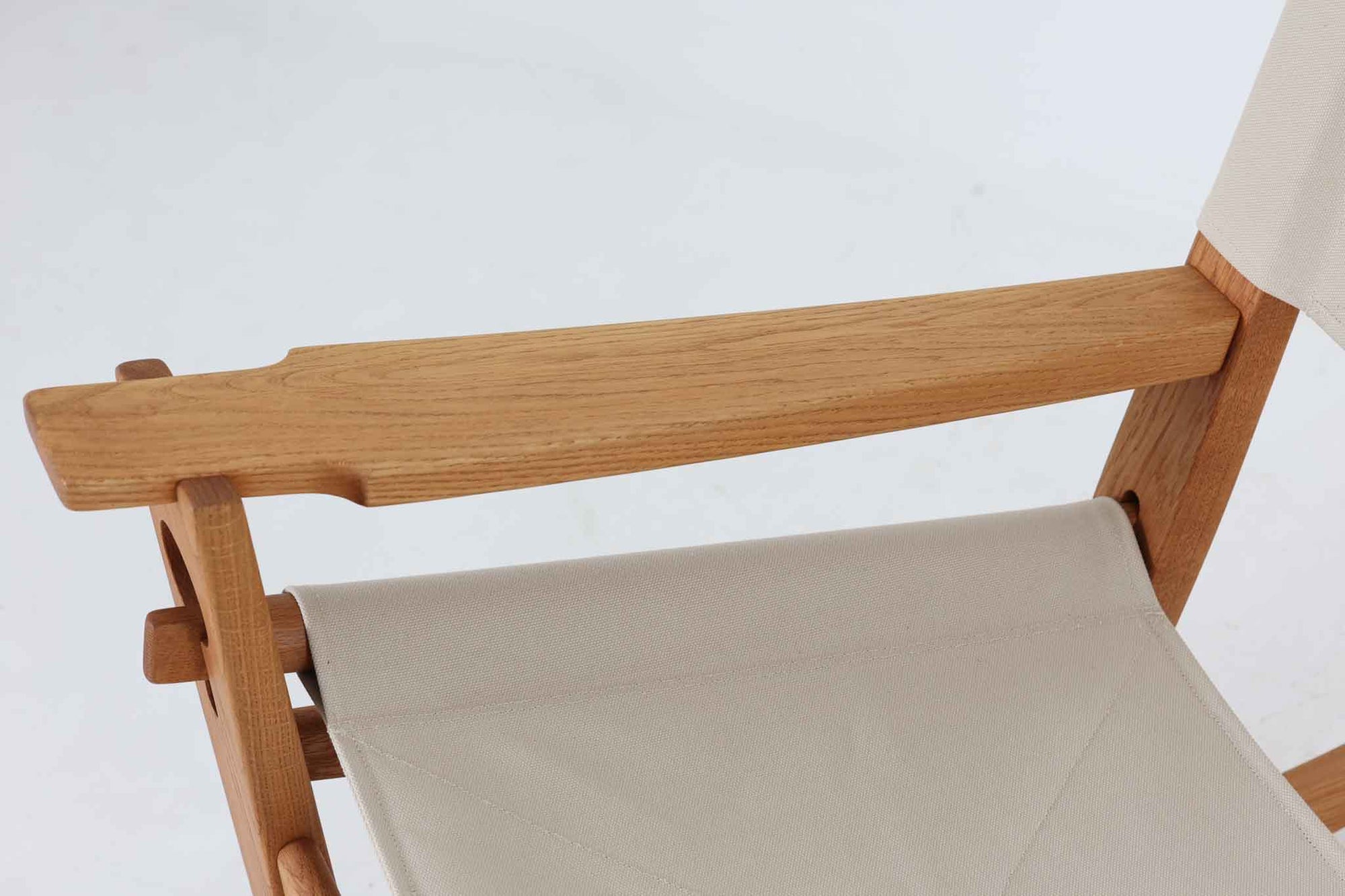 Hans J. Wegnerが1967年にデザインしたロッキングチェア「キーホールチェア（GE673）」は、GETAmA社製の一脚です。特徴的な「鍵穴」のような形状の座面固定方法が名前の由来で、左右のアーム下に引っ掛けた2本の棒が座面を支える構造です。帆布製の背もたれと座面は、ハンモックのような座り心地を提供し、まるで包み込まれるような安心感を感じさせます。ロッキングチェアならではの揺れと、程よい可動領域が特徴で、家の中でゆったりとくつろぐのに最適です。座面は簡単に取り外せ、クリーニングにも配慮されています。軽量で機能性とデザインが見事に調和した、ウェグナーならではの作品です。