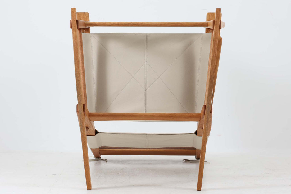 Hans J. Wegnerが1967年にデザインしたロッキングチェア「キーホールチェア（GE673）」は、GETAmA社製の一脚です。特徴的な「鍵穴」のような形状の座面固定方法が名前の由来で、左右のアーム下に引っ掛けた2本の棒が座面を支える構造です。帆布製の背もたれと座面は、ハンモックのような座り心地を提供し、まるで包み込まれるような安心感を感じさせます。ロッキングチェアならではの揺れと、程よい可動領域が特徴で、家の中でゆったりとくつろぐのに最適です。座面は簡単に取り外せ、クリーニングにも配慮されています。軽量で機能性とデザインが見事に調和した、ウェグナーならではの作品です。