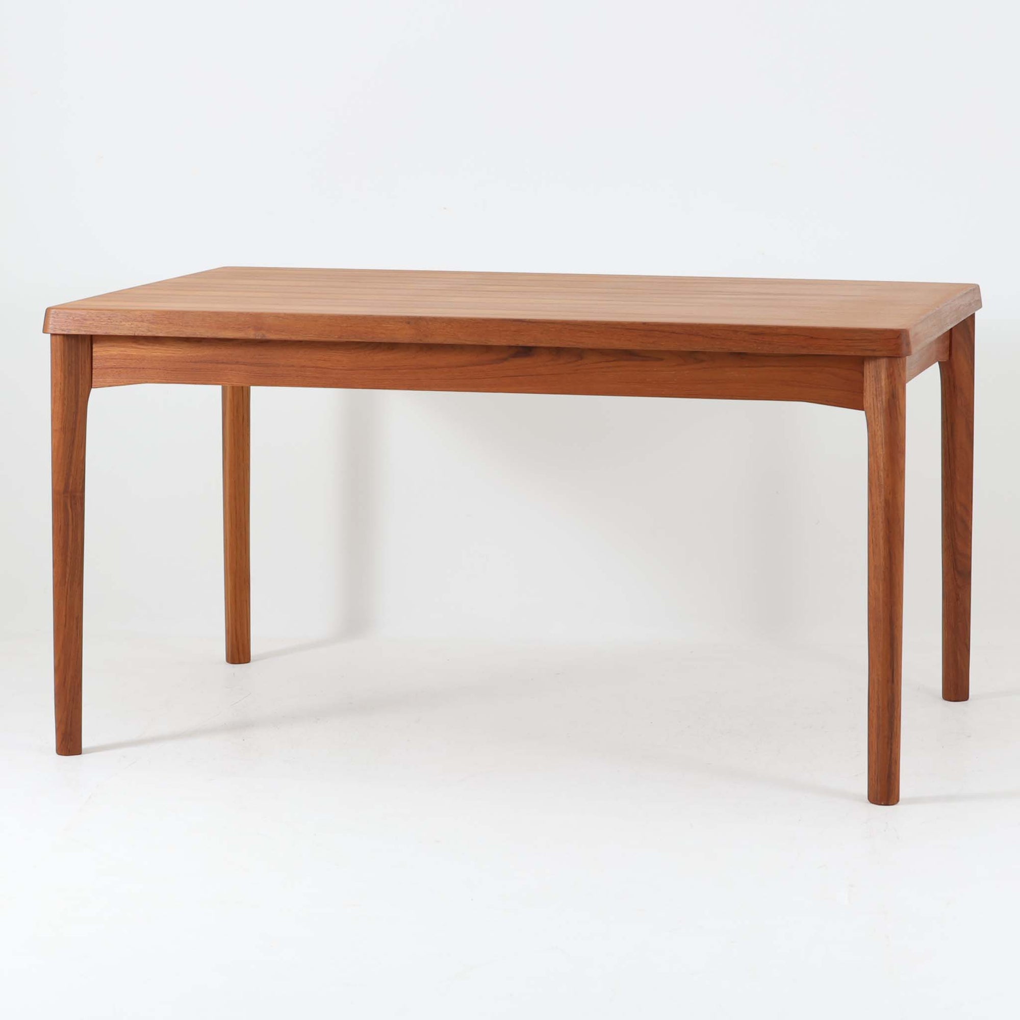 Henning Kjaernulf（ヘニング・ケアヌルフ）によってデザインされ、Vejle Stole og Mobelfabrik社が製造したデンマーク製のエクステンションダイニングテーブル。温もりあるチーク材と美しく面取りされたエッジラインが特徴です。両端のリーフを引き出すだけで最大239cmまで拡張でき、日常使いから来客時まで柔軟に対応。脚部はすっきりとした削り出しのディテールが施され、軽やかさと安定感を両立しています。素材の上質さと機能美を兼ね備えた、北欧ビンテージ家具の魅力あふれる一台です。