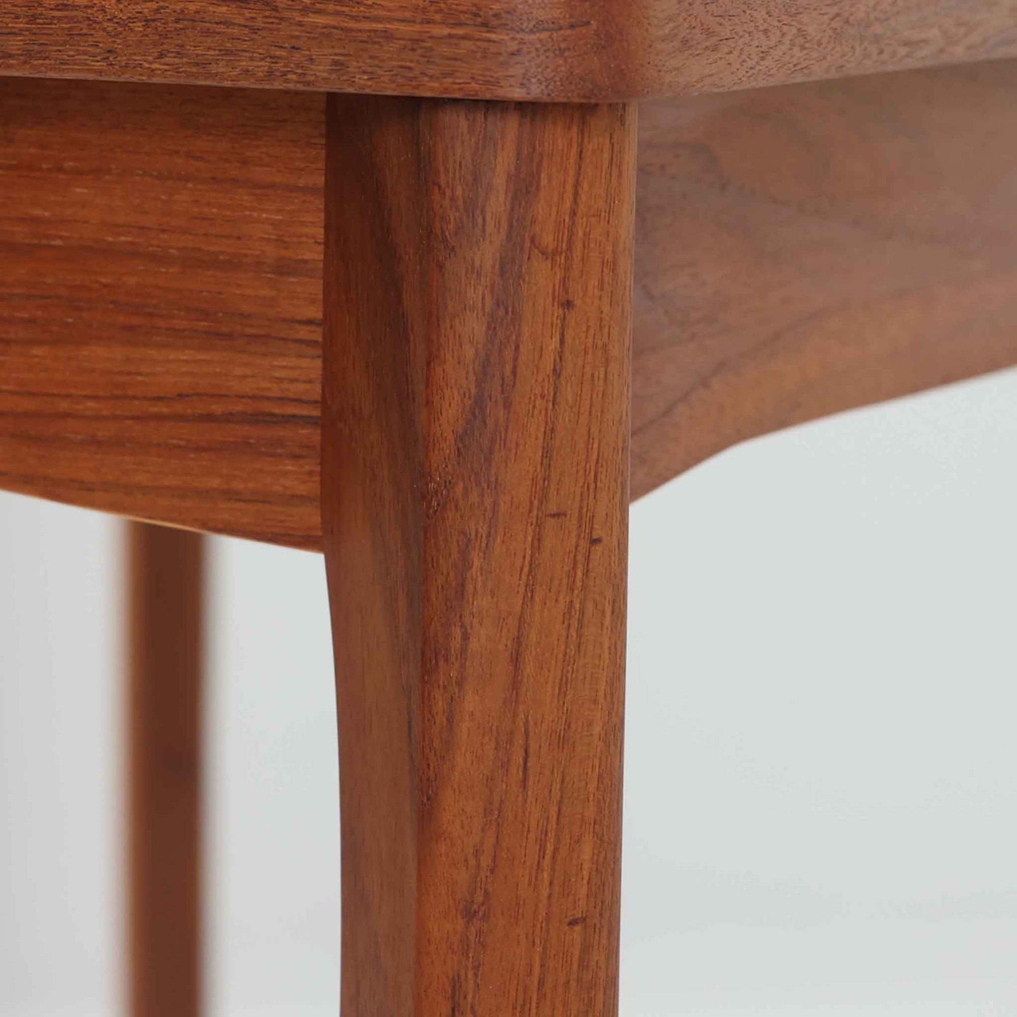 Henning Kjaernulf（ヘニング・ケアヌルフ）によってデザインされ、Vejle Stole og Mobelfabrik社が製造したデンマーク製のエクステンションダイニングテーブル。温もりあるチーク材と美しく面取りされたエッジラインが特徴です。両端のリーフを引き出すだけで最大239cmまで拡張でき、日常使いから来客時まで柔軟に対応。脚部はすっきりとした削り出しのディテールが施され、軽やかさと安定感を両立しています。素材の上質さと機能美を兼ね備えた、北欧ビンテージ家具の魅力あふれる一台です。