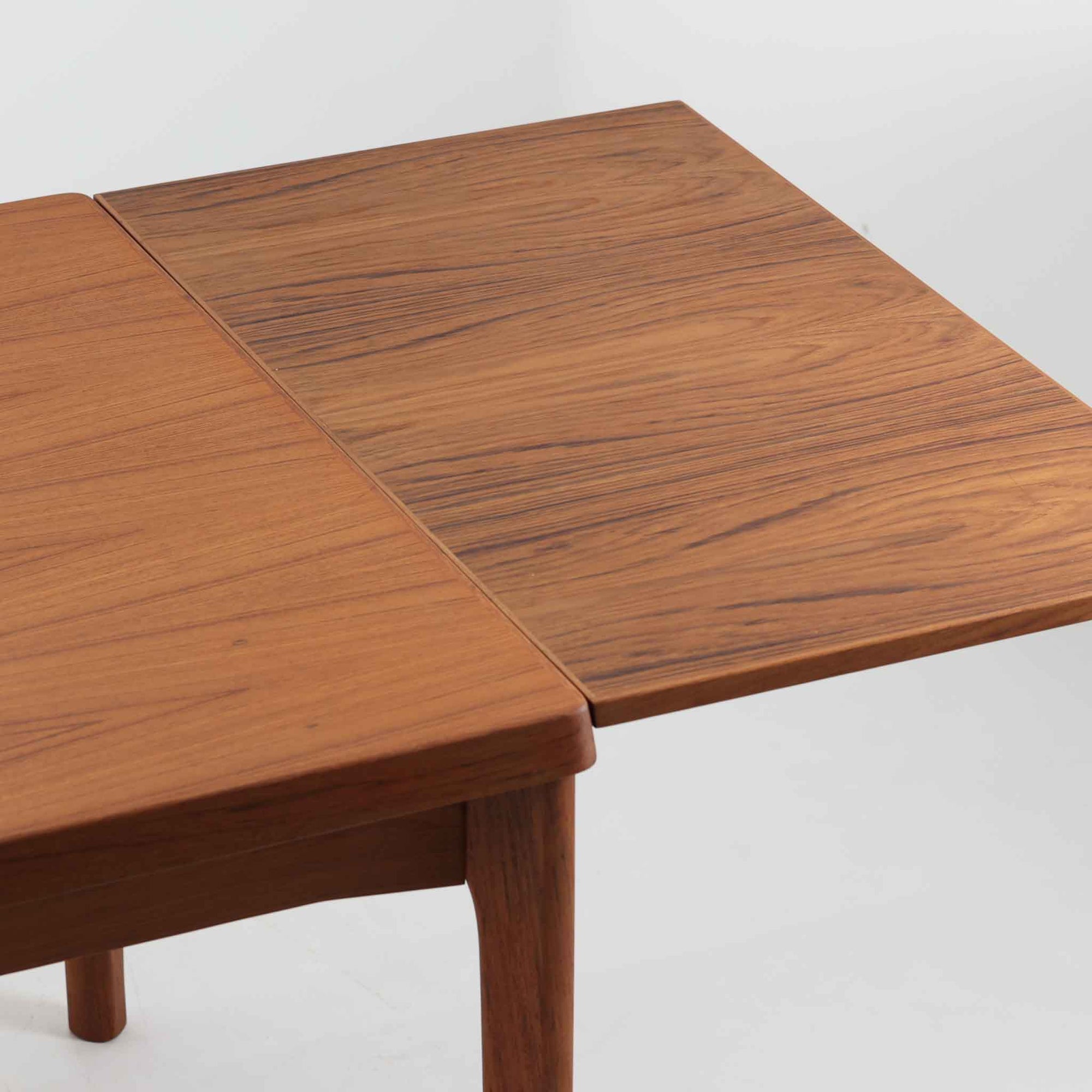 Henning Kjaernulf（ヘニング・ケアヌルフ）によってデザインされ、Vejle Stole og Mobelfabrik社が製造したデンマーク製のエクステンションダイニングテーブル。温もりあるチーク材と美しく面取りされたエッジラインが特徴です。両端のリーフを引き出すだけで最大239cmまで拡張でき、日常使いから来客時まで柔軟に対応。脚部はすっきりとした削り出しのディテールが施され、軽やかさと安定感を両立しています。素材の上質さと機能美を兼ね備えた、北欧ビンテージ家具の魅力あふれる一台です。