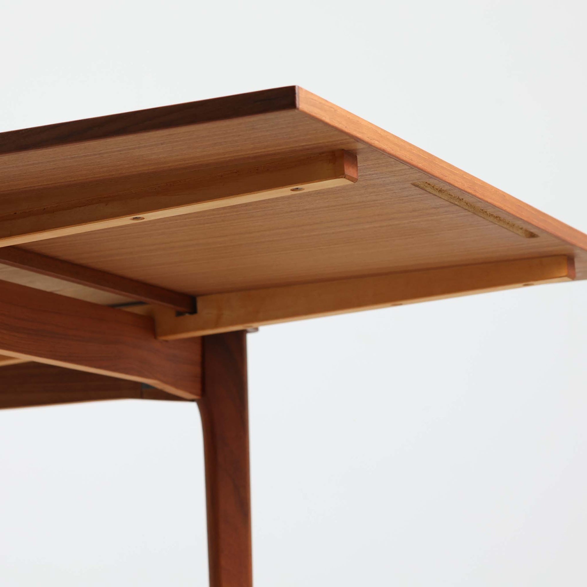 Henning Kjaernulf（ヘニング・ケアヌルフ）によってデザインされ、Vejle Stole og Mobelfabrik社が製造したデンマーク製のエクステンションダイニングテーブル。温もりあるチーク材と美しく面取りされたエッジラインが特徴です。両端のリーフを引き出すだけで最大239cmまで拡張でき、日常使いから来客時まで柔軟に対応。脚部はすっきりとした削り出しのディテールが施され、軽やかさと安定感を両立しています。素材の上質さと機能美を兼ね備えた、北欧ビンテージ家具の魅力あふれる一台です。