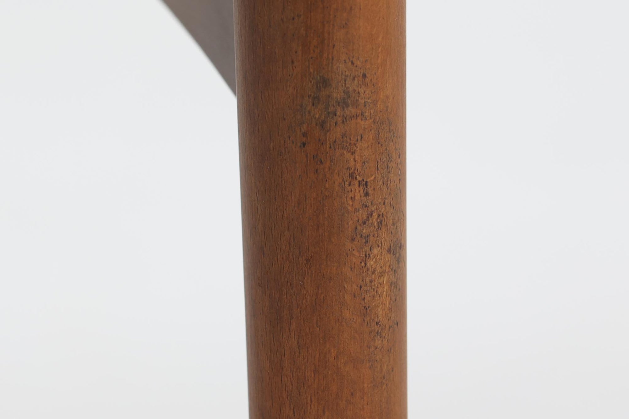 台形を基にした多角形の天板が特徴的な、美しいビンテージのセンターテーブル。心地よい木目が際立つウォールナット材の天板と、ナチュラルな風合いのビーチ材の組み合わせが、温かみのある佇まいを演出しています。天板と脚部、棚板の接続部には丸い真鍮があしらわれ、シンプルなフォルムの中に洗練されたアクセントを加えています。また、脚部をつなぐ幕板の形状も独特で、細部にまでこだわりが感じられるデザインです。デザイナーは不明ですが、細部の仕上げや素材選びから高いクオリティがうかがえる一品。モダンとクラシックが絶妙に調和した、上質なビンテージテーブルです。