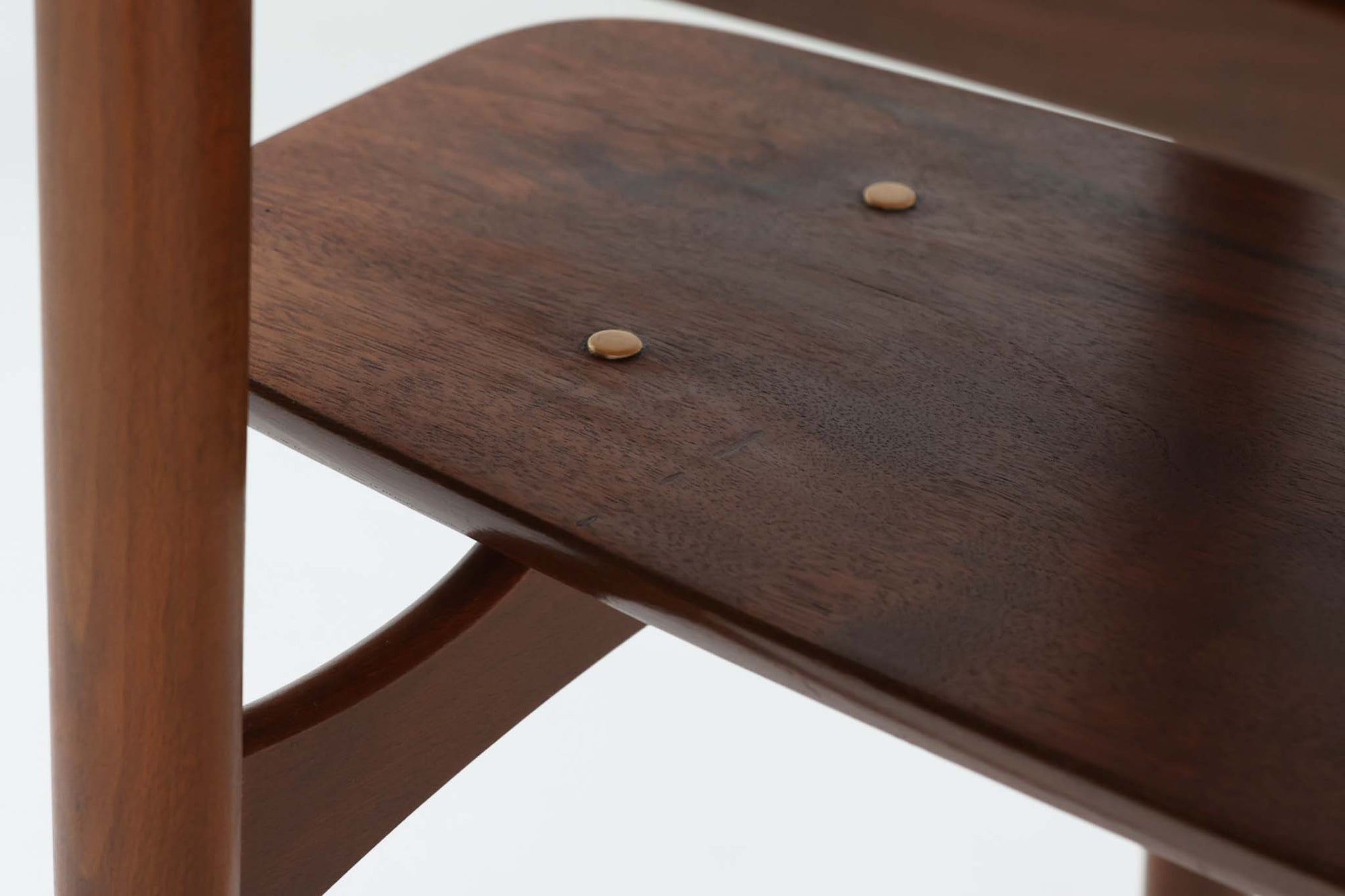 台形を基にした多角形の天板が特徴的な、美しいビンテージのセンターテーブル。心地よい木目が際立つウォールナット材の天板と、ナチュラルな風合いのビーチ材の組み合わせが、温かみのある佇まいを演出しています。天板と脚部、棚板の接続部には丸い真鍮があしらわれ、シンプルなフォルムの中に洗練されたアクセントを加えています。また、脚部をつなぐ幕板の形状も独特で、細部にまでこだわりが感じられるデザインです。デザイナーは不明ですが、細部の仕上げや素材選びから高いクオリティがうかがえる一品。モダンとクラシックが絶妙に調和した、上質なビンテージテーブルです。