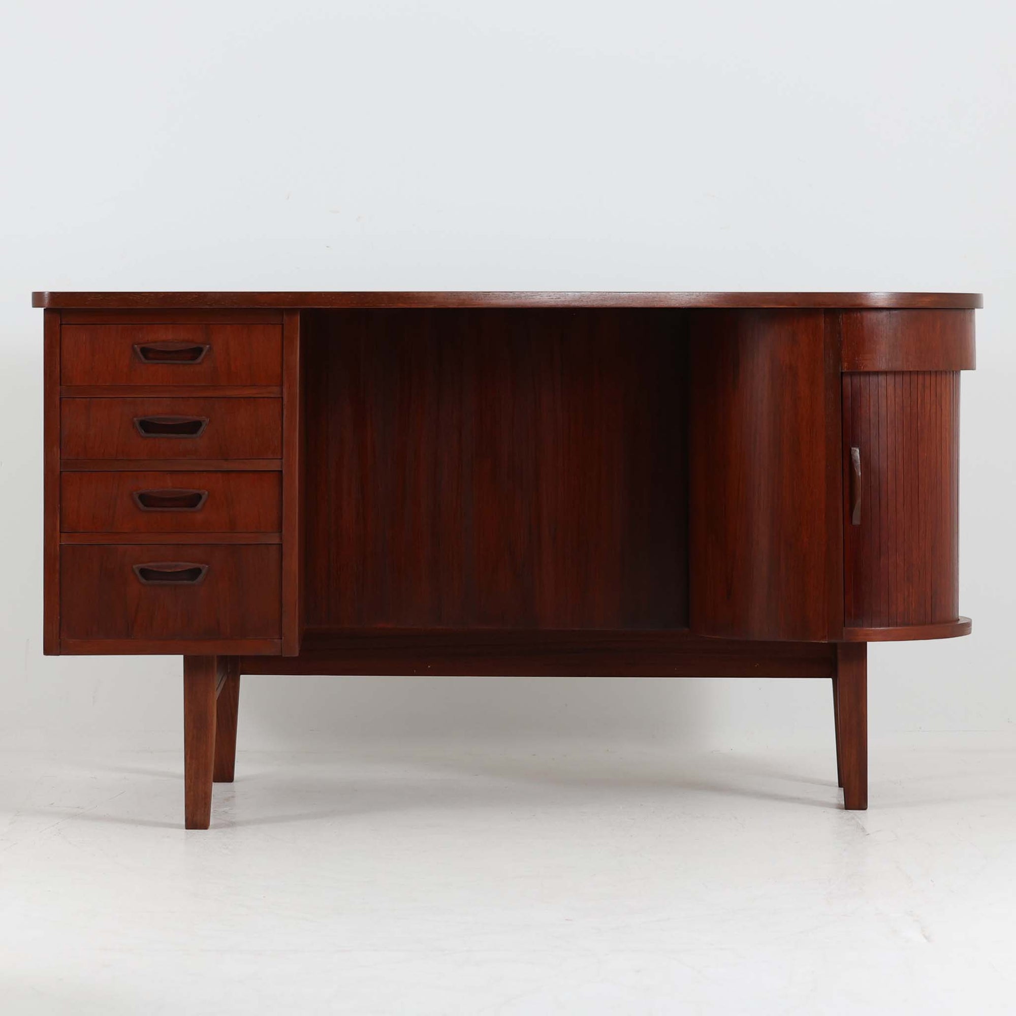 デンマーク製キドニーデスクです。緩やかな曲線を描く天板と、右側に配された蛇腹扉収納が特徴的な美しいデザインで、北欧モダンの洗練された造形美が感じられます。上質なチーク材が用いられ、深みのある色合いと木目が経年により一層味わいを増しています。背面にも収納棚を備えており、空間の中央に置いても様になる造りです。書斎デスクとしてはもちろん、ショップのカウンターや作業台としても活躍する存在感のある一台です。