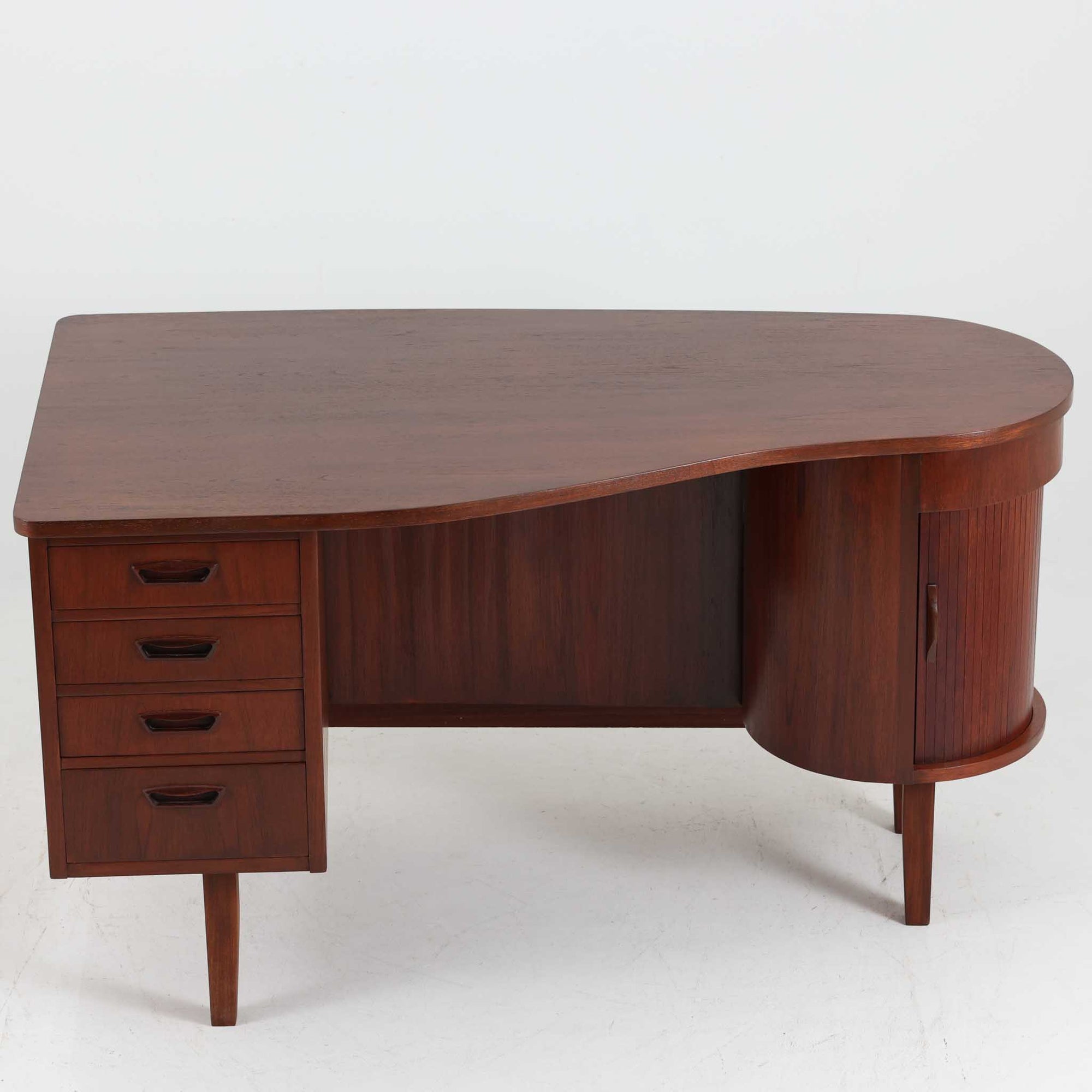 デンマーク製キドニーデスクです。緩やかな曲線を描く天板と、右側に配された蛇腹扉収納が特徴的な美しいデザインで、北欧モダンの洗練された造形美が感じられます。上質なチーク材が用いられ、深みのある色合いと木目が経年により一層味わいを増しています。背面にも収納棚を備えており、空間の中央に置いても様になる造りです。書斎デスクとしてはもちろん、ショップのカウンターや作業台としても活躍する存在感のある一台です。