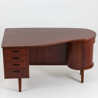 デンマーク製キドニーデスクです。緩やかな曲線を描く天板と、右側に配された蛇腹扉収納が特徴的な美しいデザインで、北欧モダンの洗練された造形美が感じられます。上質なチーク材が用いられ、深みのある色合いと木目が経年により一層味わいを増しています。背面にも収納棚を備えており、空間の中央に置いても様になる造りです。書斎デスクとしてはもちろん、ショップのカウンターや作業台としても活躍する存在感のある一台です。