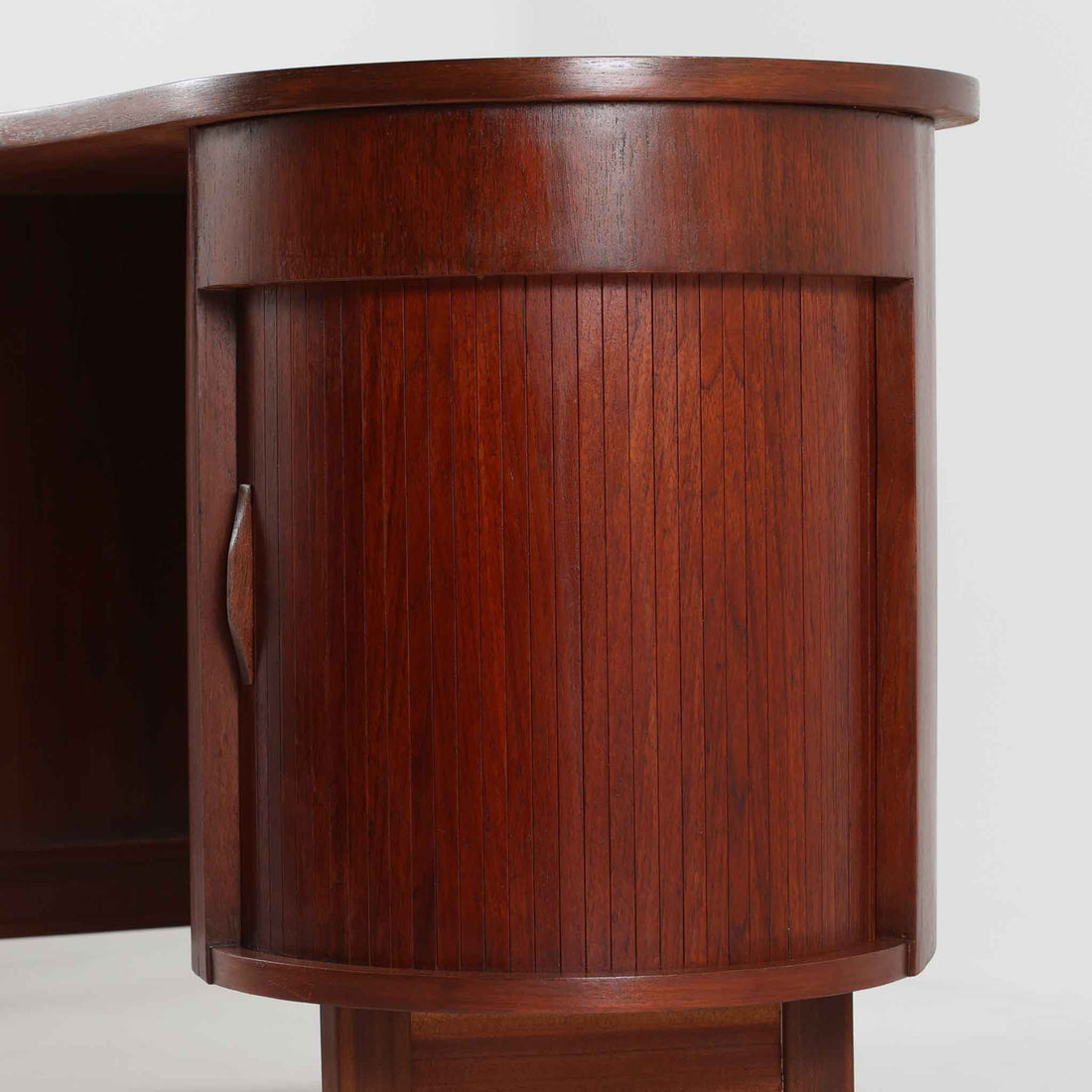 デンマーク製キドニーデスクです。緩やかな曲線を描く天板と、右側に配された蛇腹扉収納が特徴的な美しいデザインで、北欧モダンの洗練された造形美が感じられます。上質なチーク材が用いられ、深みのある色合いと木目が経年により一層味わいを増しています。背面にも収納棚を備えており、空間の中央に置いても様になる造りです。書斎デスクとしてはもちろん、ショップのカウンターや作業台としても活躍する存在感のある一台です。