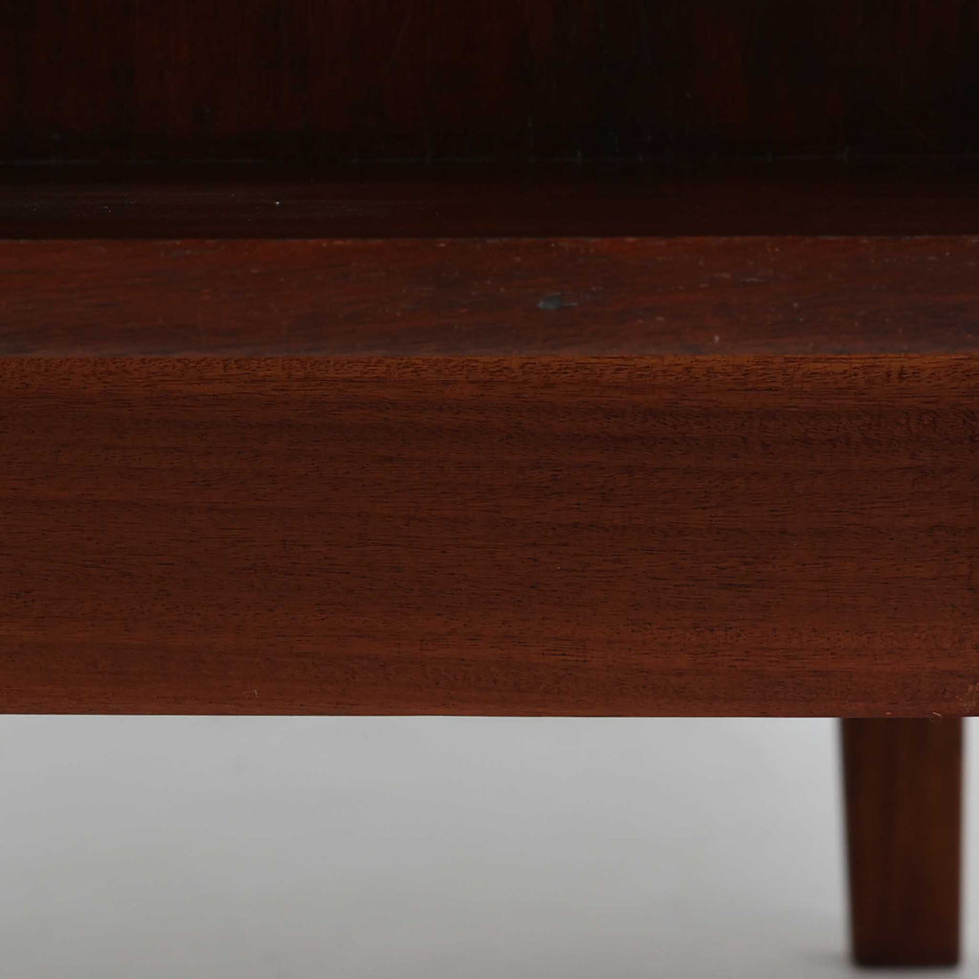 デンマーク製キドニーデスクです。緩やかな曲線を描く天板と、右側に配された蛇腹扉収納が特徴的な美しいデザインで、北欧モダンの洗練された造形美が感じられます。上質なチーク材が用いられ、深みのある色合いと木目が経年により一層味わいを増しています。背面にも収納棚を備えており、空間の中央に置いても様になる造りです。書斎デスクとしてはもちろん、ショップのカウンターや作業台としても活躍する存在感のある一台です。