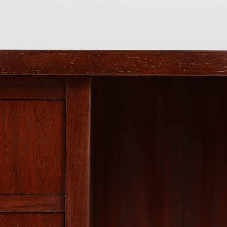 デンマーク製キドニーデスクです。緩やかな曲線を描く天板と、右側に配された蛇腹扉収納が特徴的な美しいデザインで、北欧モダンの洗練された造形美が感じられます。上質なチーク材が用いられ、深みのある色合いと木目が経年により一層味わいを増しています。背面にも収納棚を備えており、空間の中央に置いても様になる造りです。書斎デスクとしてはもちろん、ショップのカウンターや作業台としても活躍する存在感のある一台です。