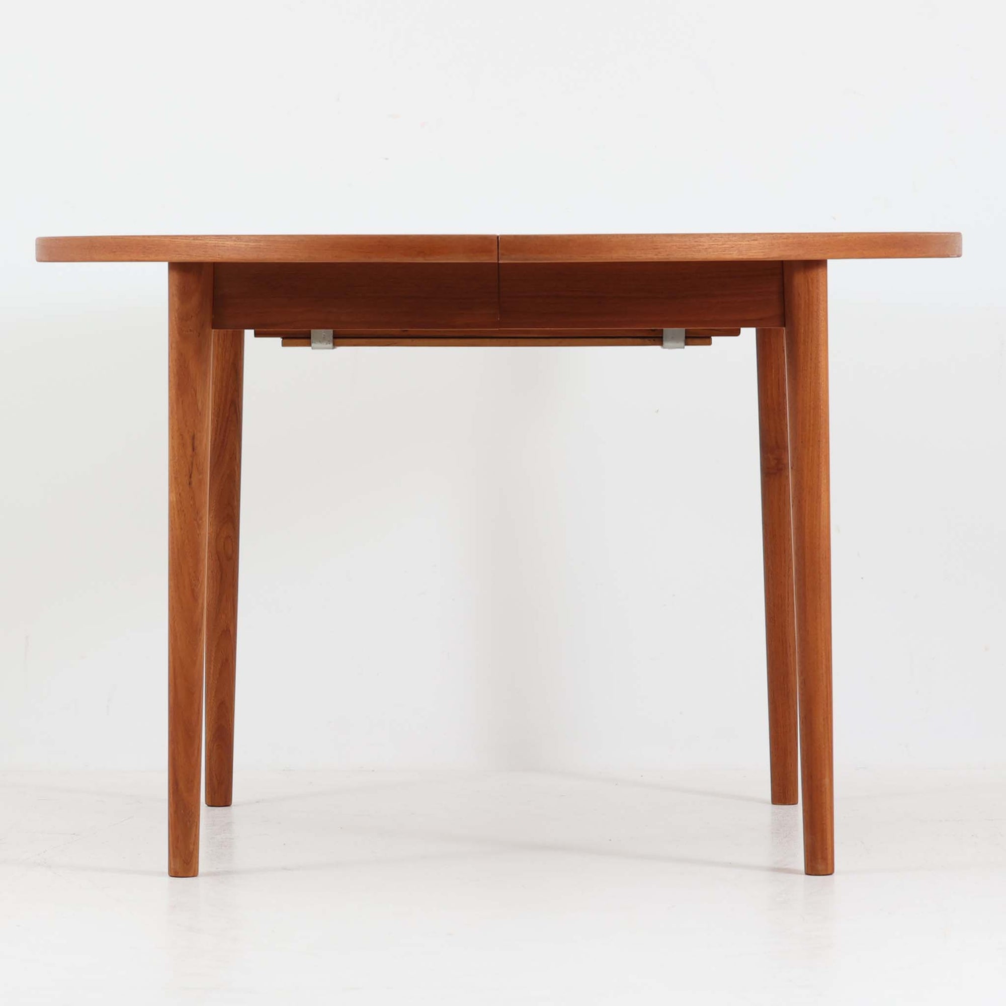 Nils Jonssonがデザインし、Troeds社より発表された円形エクステンションダイニングテーブル「Malta」です。チーク材の温かみある木目が美しく、直径110cmの天板は来客時には拡張板を追加することで大きな楕円形へと広がり、シーンに応じた柔軟な使い方が可能です。拡張板は円形では珍しく折り畳んで本体に収納することができ、機能性と利便性を兼ね備えています。脚部は細身で軽快ながら安定感があり、北欧家具らしいシンプルで機能的な構造が魅力です。日常使いはもちろん、来客時や家族の集まりにも最適で、経年による素材の風合いがビンテージならではの味わいを深めています。