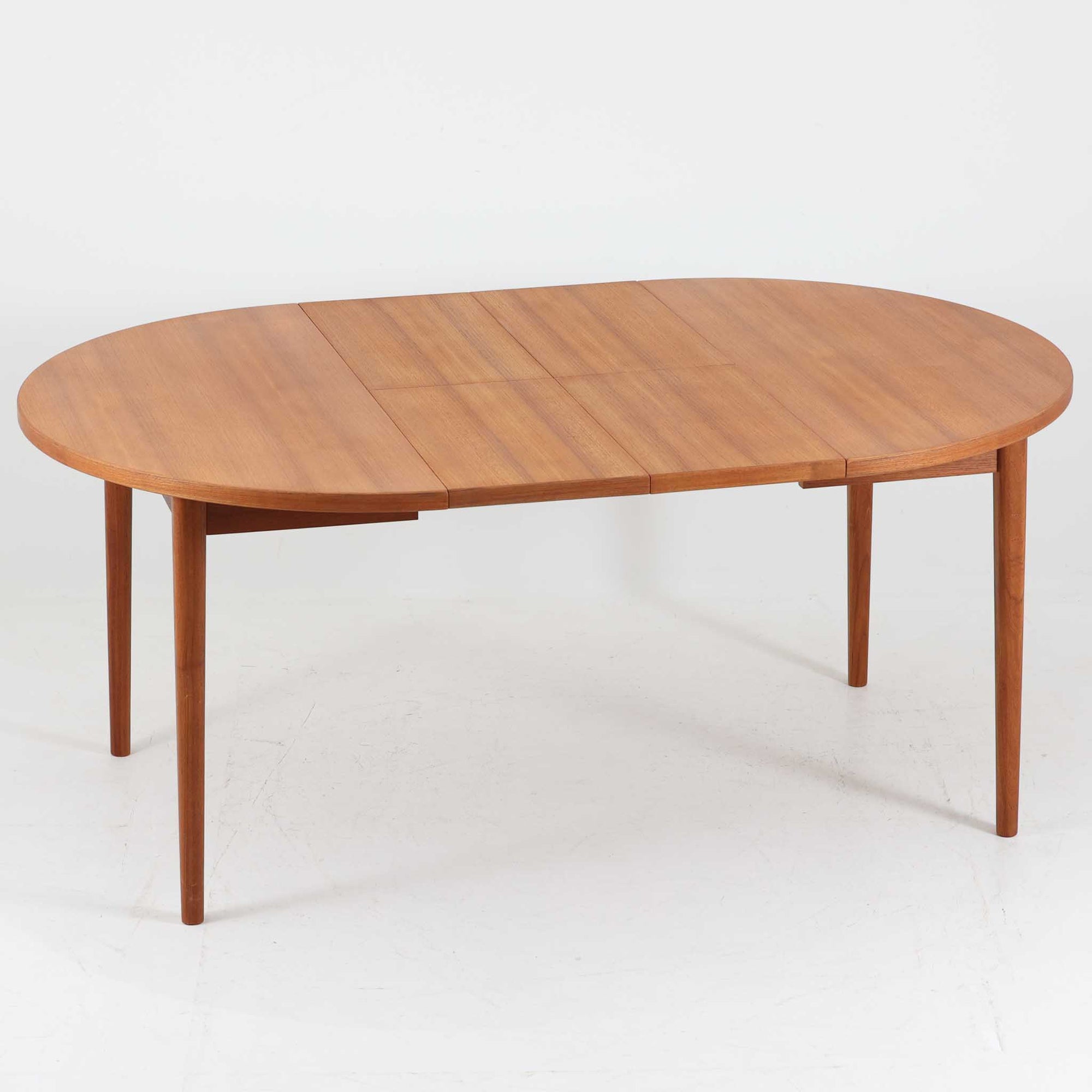 Nils Jonssonがデザインし、Troeds社より発表された円形エクステンションダイニングテーブル「Malta」です。チーク材の温かみある木目が美しく、直径110cmの天板は来客時には拡張板を追加することで大きな楕円形へと広がり、シーンに応じた柔軟な使い方が可能です。拡張板は円形では珍しく折り畳んで本体に収納することができ、機能性と利便性を兼ね備えています。脚部は細身で軽快ながら安定感があり、北欧家具らしいシンプルで機能的な構造が魅力です。日常使いはもちろん、来客時や家族の集まりにも最適で、経年による素材の風合いがビンテージならではの味わいを深めています。