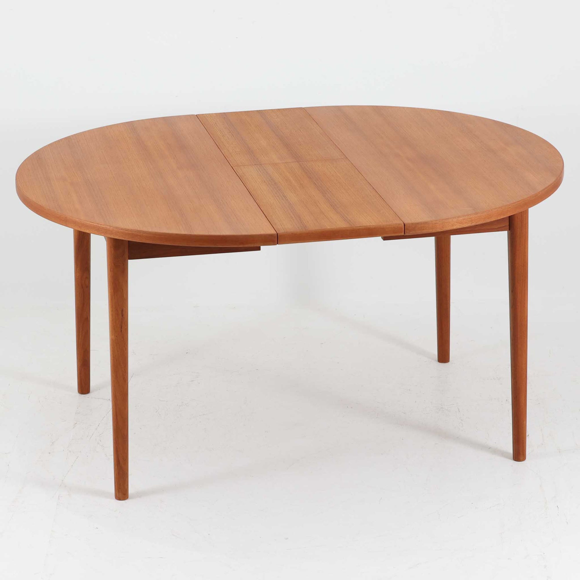 Nils Jonssonがデザインし、Troeds社より発表された円形エクステンションダイニングテーブル「Malta」です。チーク材の温かみある木目が美しく、直径110cmの天板は来客時には拡張板を追加することで大きな楕円形へと広がり、シーンに応じた柔軟な使い方が可能です。拡張板は円形では珍しく折り畳んで本体に収納することができ、機能性と利便性を兼ね備えています。脚部は細身で軽快ながら安定感があり、北欧家具らしいシンプルで機能的な構造が魅力です。日常使いはもちろん、来客時や家族の集まりにも最適で、経年による素材の風合いがビンテージならではの味わいを深めています。