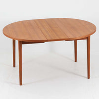 Nils Jonssonがデザインし、Troeds社より発表された円形エクステンションダイニングテーブル「Malta」です。チーク材の温かみある木目が美しく、直径110cmの天板は来客時には拡張板を追加することで大きな楕円形へと広がり、シーンに応じた柔軟な使い方が可能です。拡張板は円形では珍しく折り畳んで本体に収納することができ、機能性と利便性を兼ね備えています。脚部は細身で軽快ながら安定感があり、北欧家具らしいシンプルで機能的な構造が魅力です。日常使いはもちろん、来客時や家族の集まりにも最適で、経年による素材の風合いがビンテージならではの味わいを深めています。