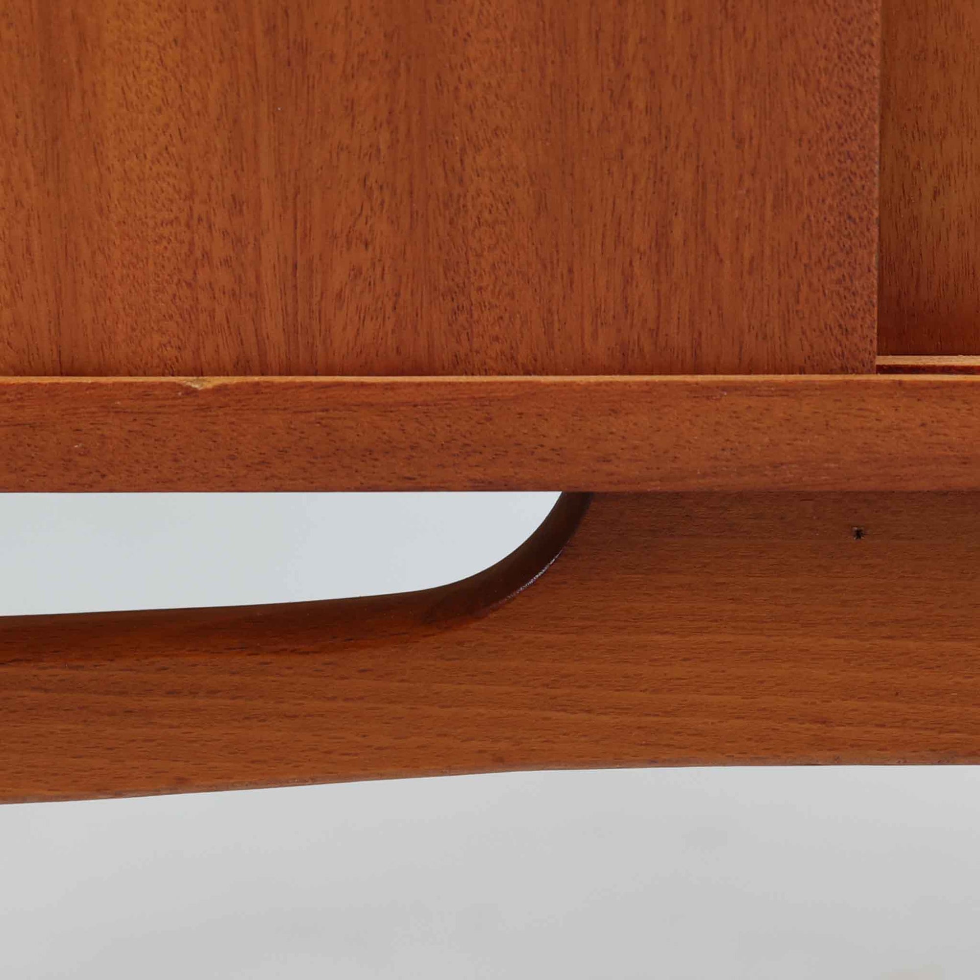 スウェーデンの老舗家具メーカー、Svenssons Mobler社によるマホガニー材のディスプレイシェルフです。上部の3段シェルフは高さを調整できる可動棚仕様で、書籍やオブジェ、植物などをバランス良く飾ることができます。下段のスライド扉収納は実用性が高く、生活感をすっきりと隠せる構造です。滑らかな木肌と温かみのある赤褐色の木目がマホガニーならではの上品な雰囲気を醸し出します。脚部の細身なテーパー形状も美しく、空間に軽やかさを添える北欧ビンテージ家具です。スライド扉の取っ手部分は丸くくり抜かれており、シンプルながらも洗練された印象を与えます。収納部と棚板の両サイドに開けられた穴に支柱を通して組み立てる独特の構造が特徴で、機能性とデザイン性を兼ね備えたスウェーデンらしい巧みな造りです。