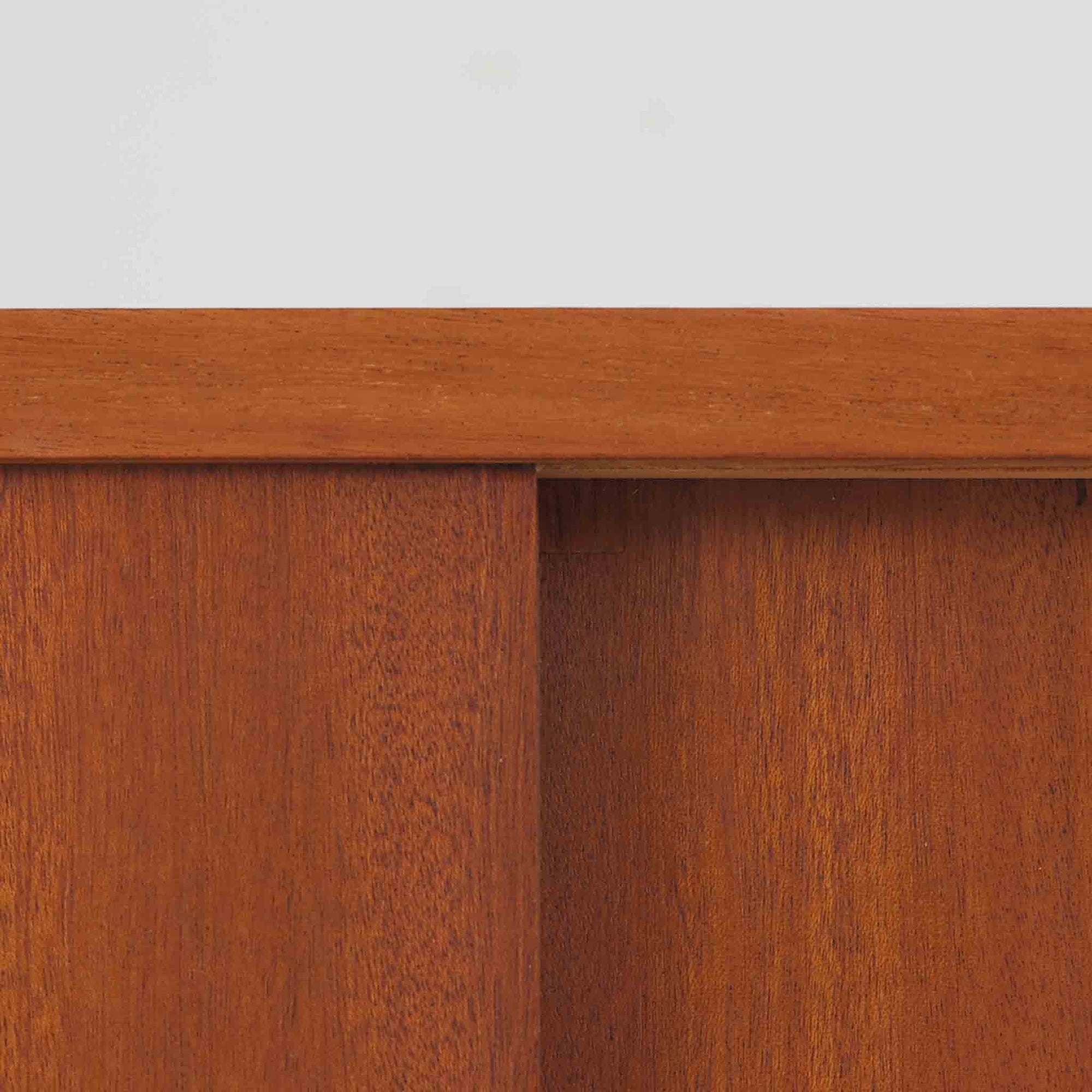 スウェーデンの老舗家具メーカー、Svenssons Mobler社によるマホガニー材のディスプレイシェルフです。上部の3段シェルフは高さを調整できる可動棚仕様で、書籍やオブジェ、植物などをバランス良く飾ることができます。下段のスライド扉収納は実用性が高く、生活感をすっきりと隠せる構造です。滑らかな木肌と温かみのある赤褐色の木目がマホガニーならではの上品な雰囲気を醸し出します。脚部の細身なテーパー形状も美しく、空間に軽やかさを添える北欧ビンテージ家具です。スライド扉の取っ手部分は丸くくり抜かれており、シンプルながらも洗練された印象を与えます。収納部と棚板の両サイドに開けられた穴に支柱を通して組み立てる独特の構造が特徴で、機能性とデザイン性を兼ね備えたスウェーデンらしい巧みな造りです。