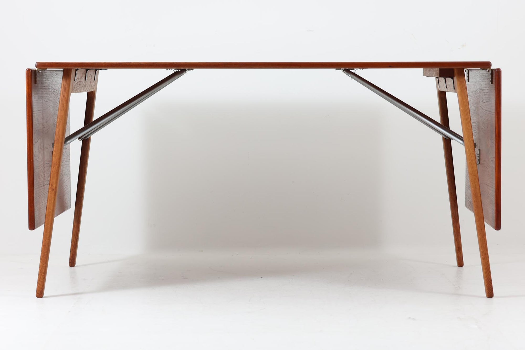 北欧から買い付けた、Børge mogensenデザインのmodel 162です。「DESIGN mUSEUm DANmARK」によれば、このモデルは1953年にデザインされたものです。Børge mogensenの作品としては珍しく、金属と木材を組み合わせたデザインが特徴です。天板には、色味の濃い高品質なチーク材が使用され、脚部はナチュラルな色合いのスリムなデザインが採用されています。また、補強材として使用されたスチールの色合いとの調和により、全体的に非常に洗練された印象を与えつつも、スチールにより高い強度が確保されています。天板中央のビスを外すことで、テーブルは折り畳み可能となり、引っ越し時の搬入や搬出も安心して行えます。