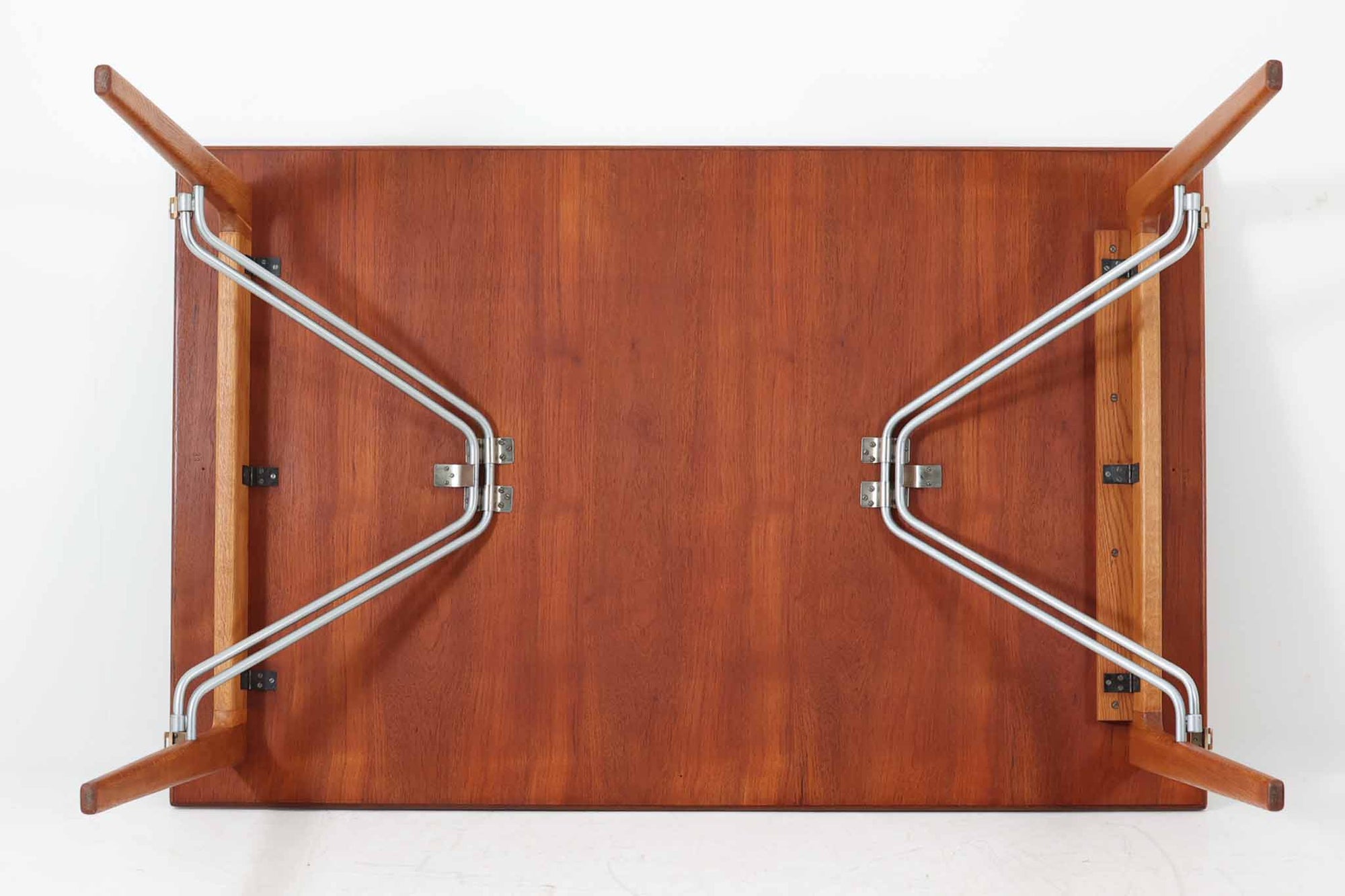 北欧から買い付けた、Børge mogensenデザインのmodel 162です。「DESIGN mUSEUm DANmARK」によれば、このモデルは1953年にデザインされたものです。Børge mogensenの作品としては珍しく、金属と木材を組み合わせたデザインが特徴です。天板には、色味の濃い高品質なチーク材が使用され、脚部はナチュラルな色合いのスリムなデザインが採用されています。また、補強材として使用されたスチールの色合いとの調和により、全体的に非常に洗練された印象を与えつつも、スチールにより高い強度が確保されています。天板中央のビスを外すことで、テーブルは折り畳み可能となり、引っ越し時の搬入や搬出も安心して行えます。