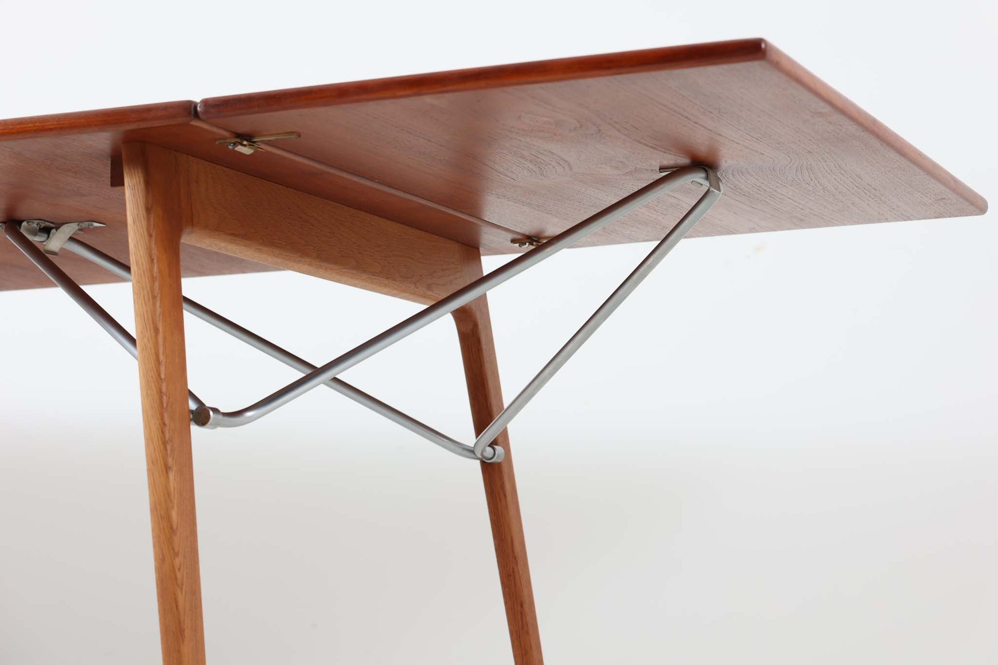 北欧から買い付けた、Børge mogensenデザインのmodel 162です。「DESIGN mUSEUm DANmARK」によれば、このモデルは1953年にデザインされたものです。Børge mogensenの作品としては珍しく、金属と木材を組み合わせたデザインが特徴です。天板には、色味の濃い高品質なチーク材が使用され、脚部はナチュラルな色合いのスリムなデザインが採用されています。また、補強材として使用されたスチールの色合いとの調和により、全体的に非常に洗練された印象を与えつつも、スチールにより高い強度が確保されています。天板中央のビスを外すことで、テーブルは折り畳み可能となり、引っ越し時の搬入や搬出も安心して行えます。