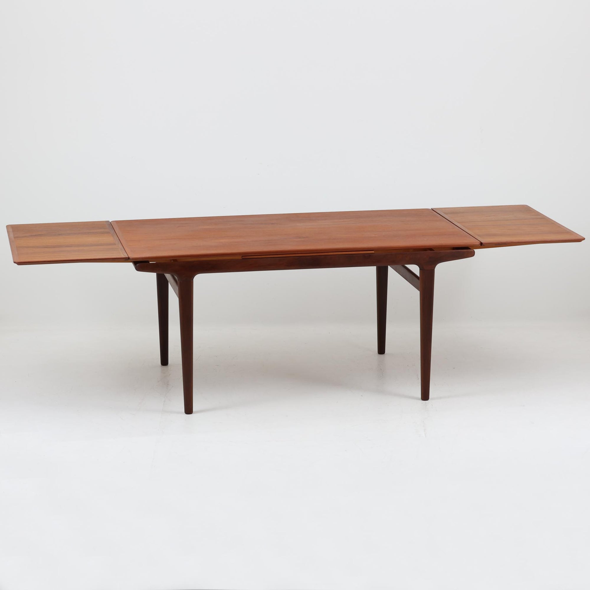 Johannes Andersenデザイン、Uldum Mobelfabrik社製のエクステンションダイニングテーブルです。チーク材特有の温かみある色調と繊細な木目が美しく、北欧家具らしい洗練された雰囲気を漂わせます。幅160cmから最大261cmまで拡張可能で、来客時や家族の集まりなどに柔軟に対応できる実用性の高さも魅力です。丸みを帯びたエッジや脚部の優雅な曲線など、アンダーセンならではの造形美が感じられる逸品で、ビンテージならではの風格と存在感を備えています。