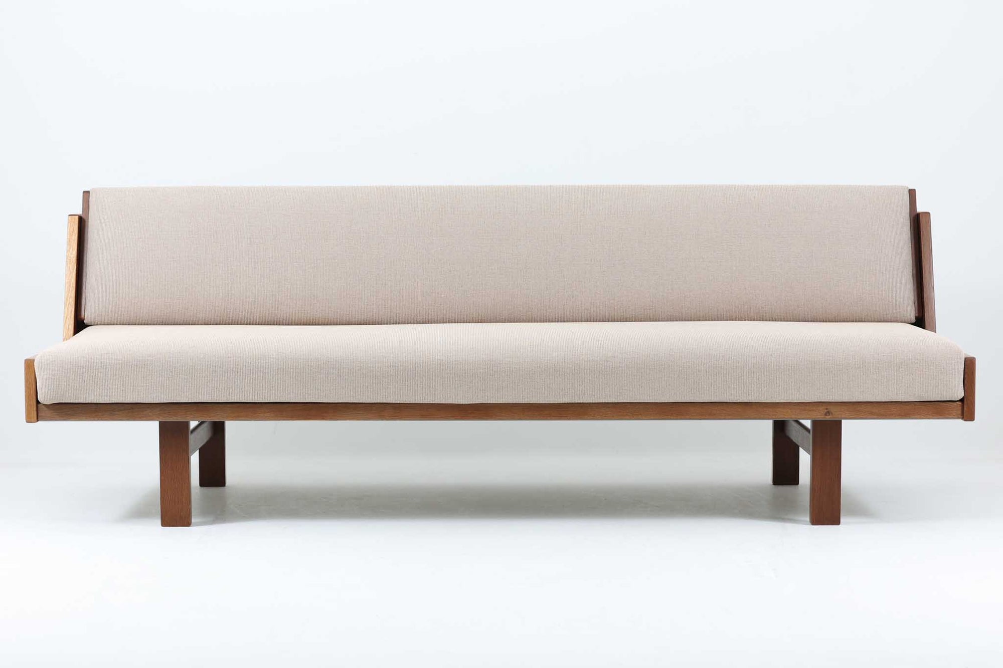 デンマークの老舗家具メーカーGetama（ゲタマ）製、Hans J. Wegner（ハンス・J・ウェグナー）デザインの名作デイベッド「GE258」です。フレームには深みのあるダークオーク材を使用しており、落ち着いた色味と上品な木目が魅力です。背もたれは後方に倒すことでベッドとして使用可能な構造で、ミニマルで美しいラインと機能性を兼ね備えた北欧デザインの代表作です。クッションはベージュ系のファブリックにて張り替え済みで、モダンでやわらかな印象を与えます。リビングやゲストルームにも最適な一台です。