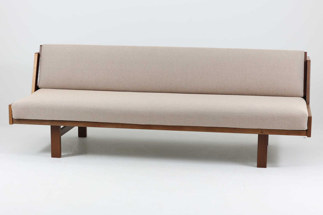 デンマークの老舗家具メーカーGetama（ゲタマ）製、Hans J. Wegner（ハンス・J・ウェグナー）デザインの名作デイベッド「GE258」です。フレームには深みのあるダークオーク材を使用しており、落ち着いた色味と上品な木目が魅力です。背もたれは後方に倒すことでベッドとして使用可能な構造で、ミニマルで美しいラインと機能性を兼ね備えた北欧デザインの代表作です。クッションはベージュ系のファブリックにて張り替え済みで、モダンでやわらかな印象を与えます。リビングやゲストルームにも最適な一台です。