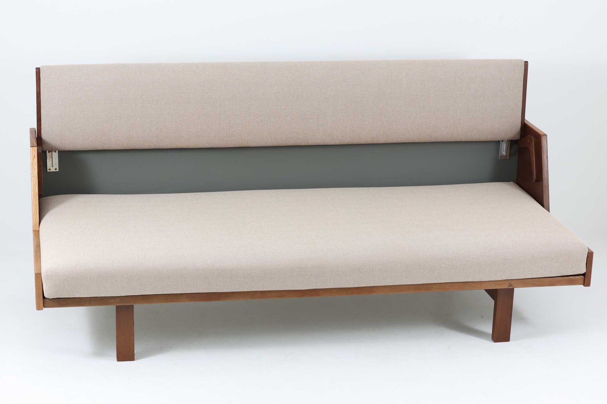 デンマークの老舗家具メーカーGetama（ゲタマ）製、Hans J. Wegner（ハンス・J・ウェグナー）デザインの名作デイベッド「GE258」です。フレームには深みのあるダークオーク材を使用しており、落ち着いた色味と上品な木目が魅力です。背もたれは後方に倒すことでベッドとして使用可能な構造で、ミニマルで美しいラインと機能性を兼ね備えた北欧デザインの代表作です。クッションはベージュ系のファブリックにて張り替え済みで、モダンでやわらかな印象を与えます。リビングやゲストルームにも最適な一台です。