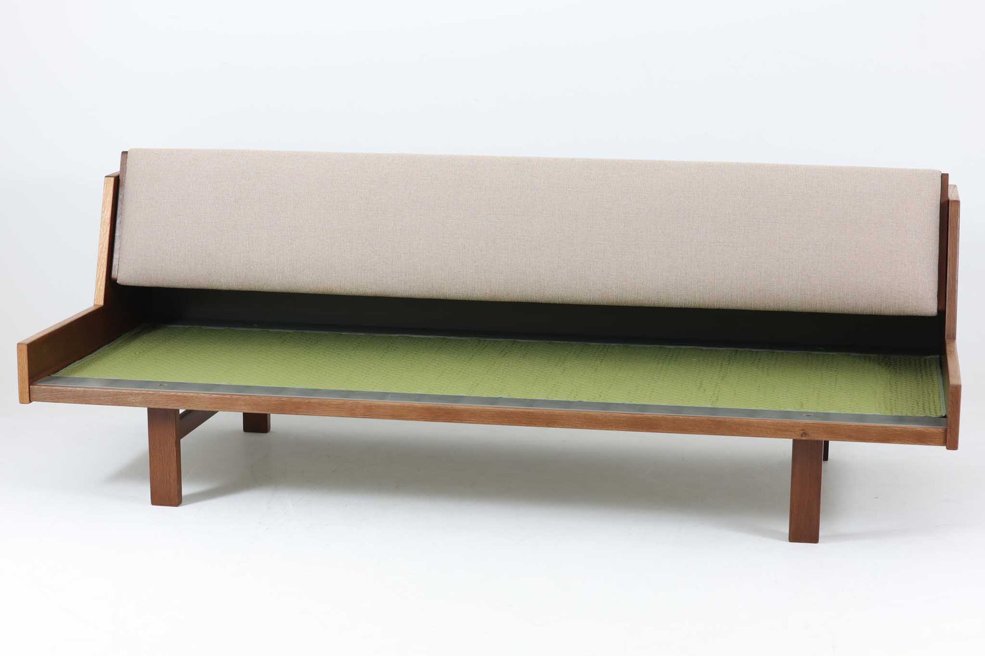 デンマークの老舗家具メーカーGetama（ゲタマ）製、Hans J. Wegner（ハンス・J・ウェグナー）デザインの名作デイベッド「GE258」です。フレームには深みのあるダークオーク材を使用しており、落ち着いた色味と上品な木目が魅力です。背もたれは後方に倒すことでベッドとして使用可能な構造で、ミニマルで美しいラインと機能性を兼ね備えた北欧デザインの代表作です。クッションはベージュ系のファブリックにて張り替え済みで、モダンでやわらかな印象を与えます。リビングやゲストルームにも最適な一台です。