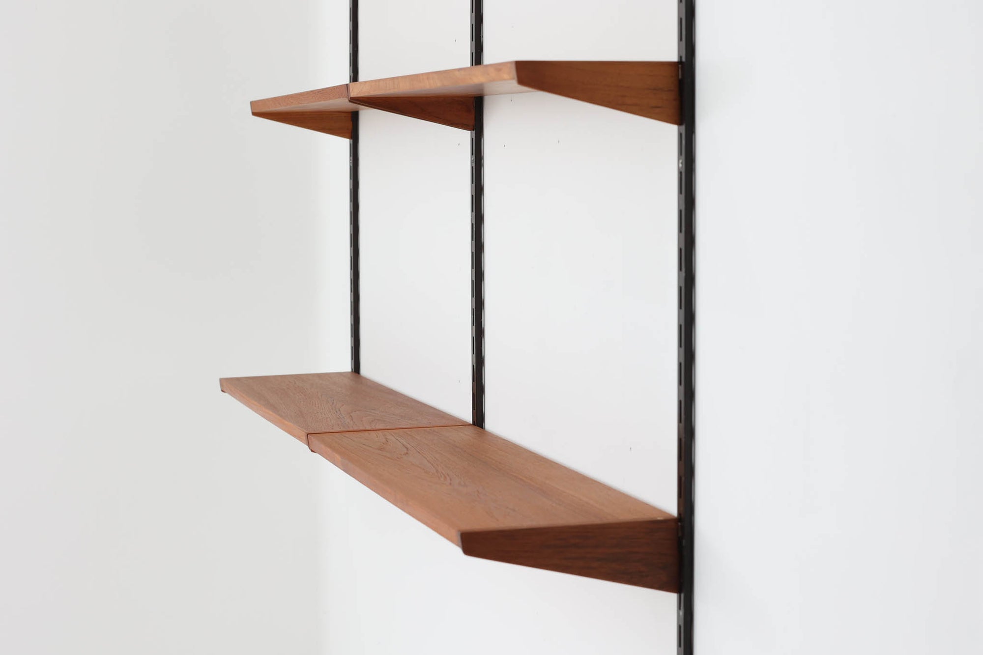 このウォールシェルフは、デンマークの有名デザイナー、カイ・クリスチャンセンがデザインしたもので、Fm furnitureから発売されました。フレームを壁面に取り付け、棚板を好きな位置に配置する事が出来ます。写真の様に2列で使用する以外にも、1列で使用する事も可能です。