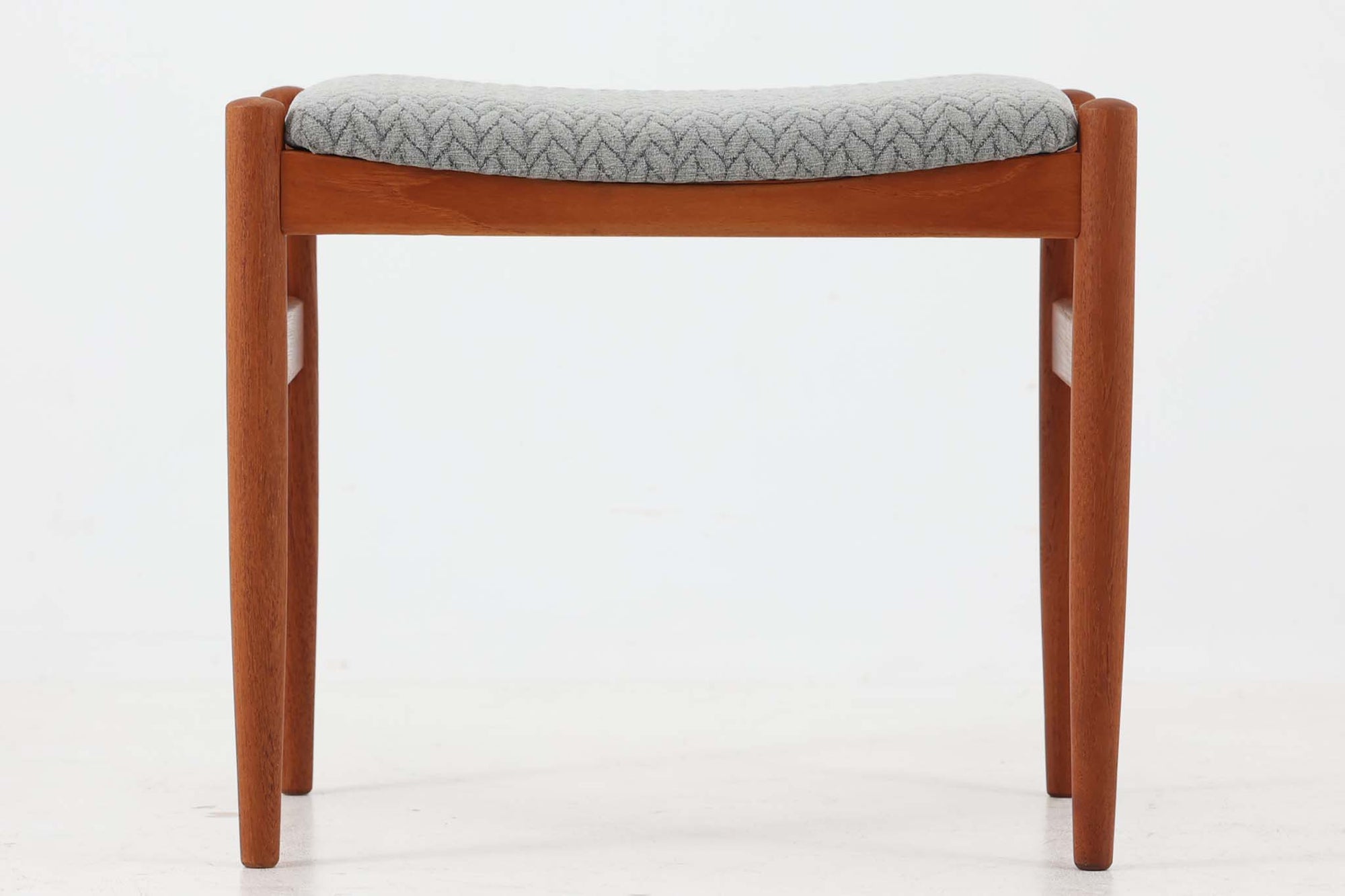 こちらはデンマーク製のスツールです。フレームには良質なチーク材が使用されており、美しい木目が特徴です。高さは約42cmと珍しい寸法で、一般的な椅子の座面に近い高さとなっています。座面は内部のウレタンを厚みのあるものに交換し、張り替えを施しておりますので、快適な座り心地をお楽しみいただけます。柔らかい印象の三つ編み柄の生地を使用いたしました。