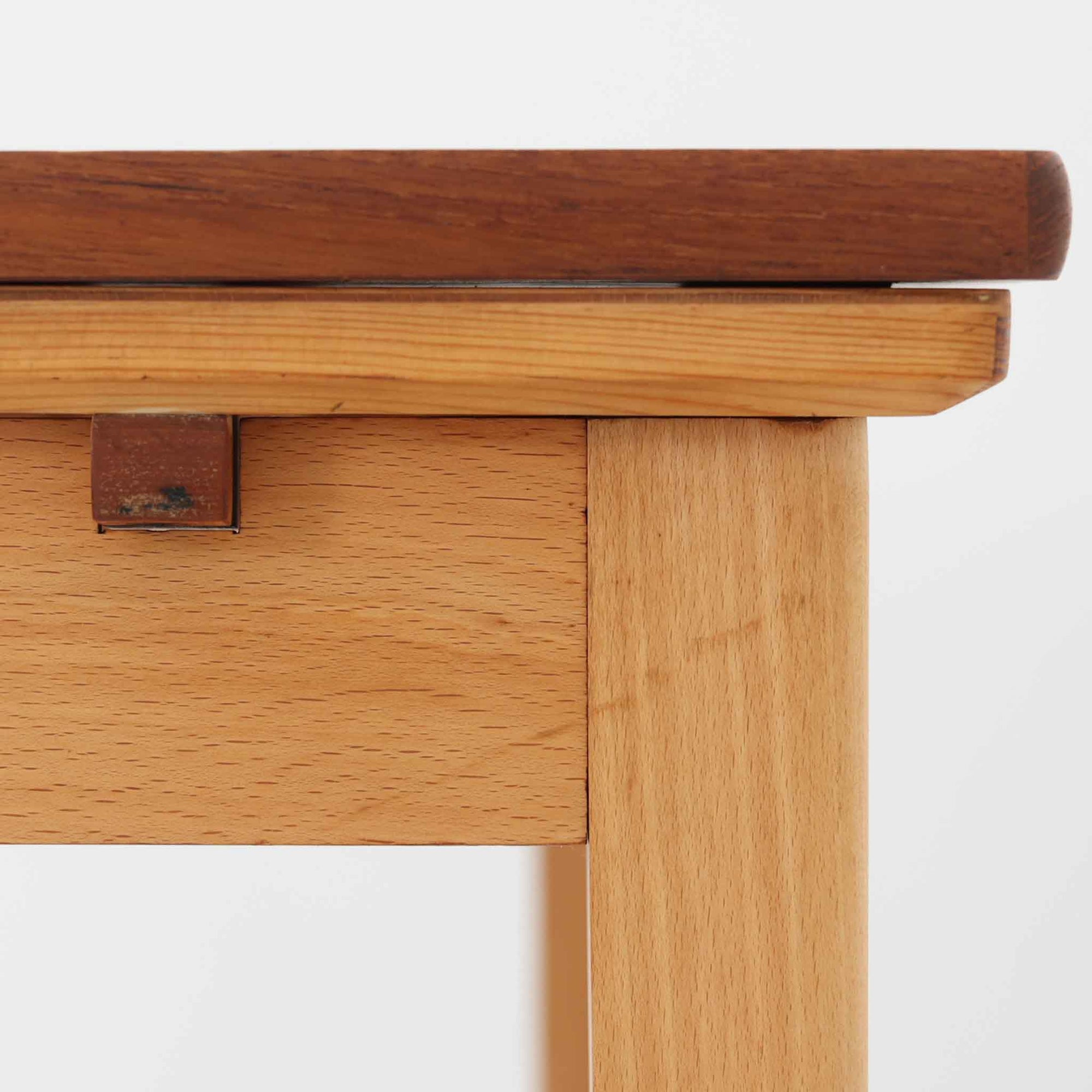 チーク材とビーチ材を組み合わせたデンマーク製のエクステンションダイニングテーブル。天板には深みのあるチーク材、脚部、幕板、拡張板には明るいビーチ材を使用し、異素材のコントラストが洗練された印象を与えます。幅100cmとコンパクトながら、両側に伸長式リーフを備え、用途に応じて天板の拡張が可能。シンプルで堅牢なつくりは、限られた空間にもフィットし、経年変化による木材の味わいとともに、長く愛用できる北欧ビンテージ家具の魅力が詰まった一台です。