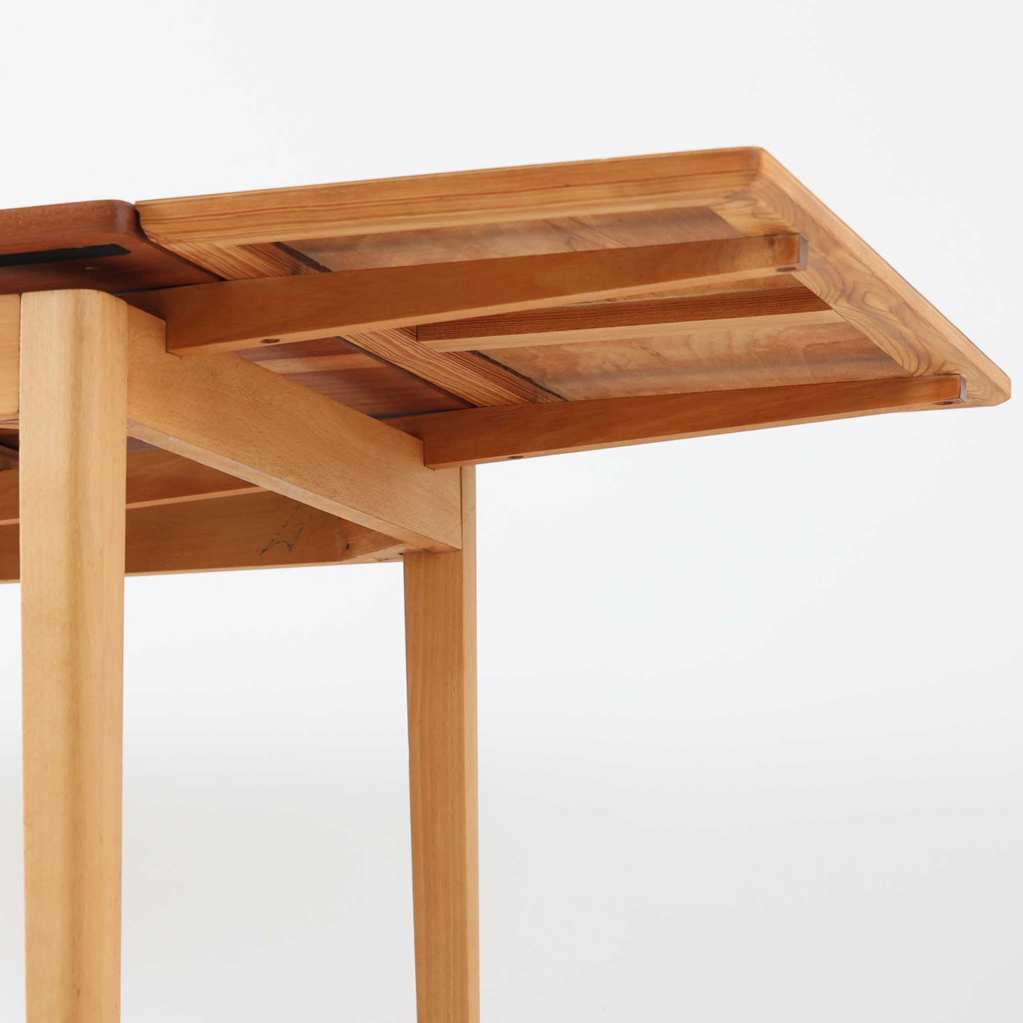 チーク材とビーチ材を組み合わせたデンマーク製のエクステンションダイニングテーブル。天板には深みのあるチーク材、脚部、幕板、拡張板には明るいビーチ材を使用し、異素材のコントラストが洗練された印象を与えます。幅100cmとコンパクトながら、両側に伸長式リーフを備え、用途に応じて天板の拡張が可能。シンプルで堅牢なつくりは、限られた空間にもフィットし、経年変化による木材の味わいとともに、長く愛用できる北欧ビンテージ家具の魅力が詰まった一台です。