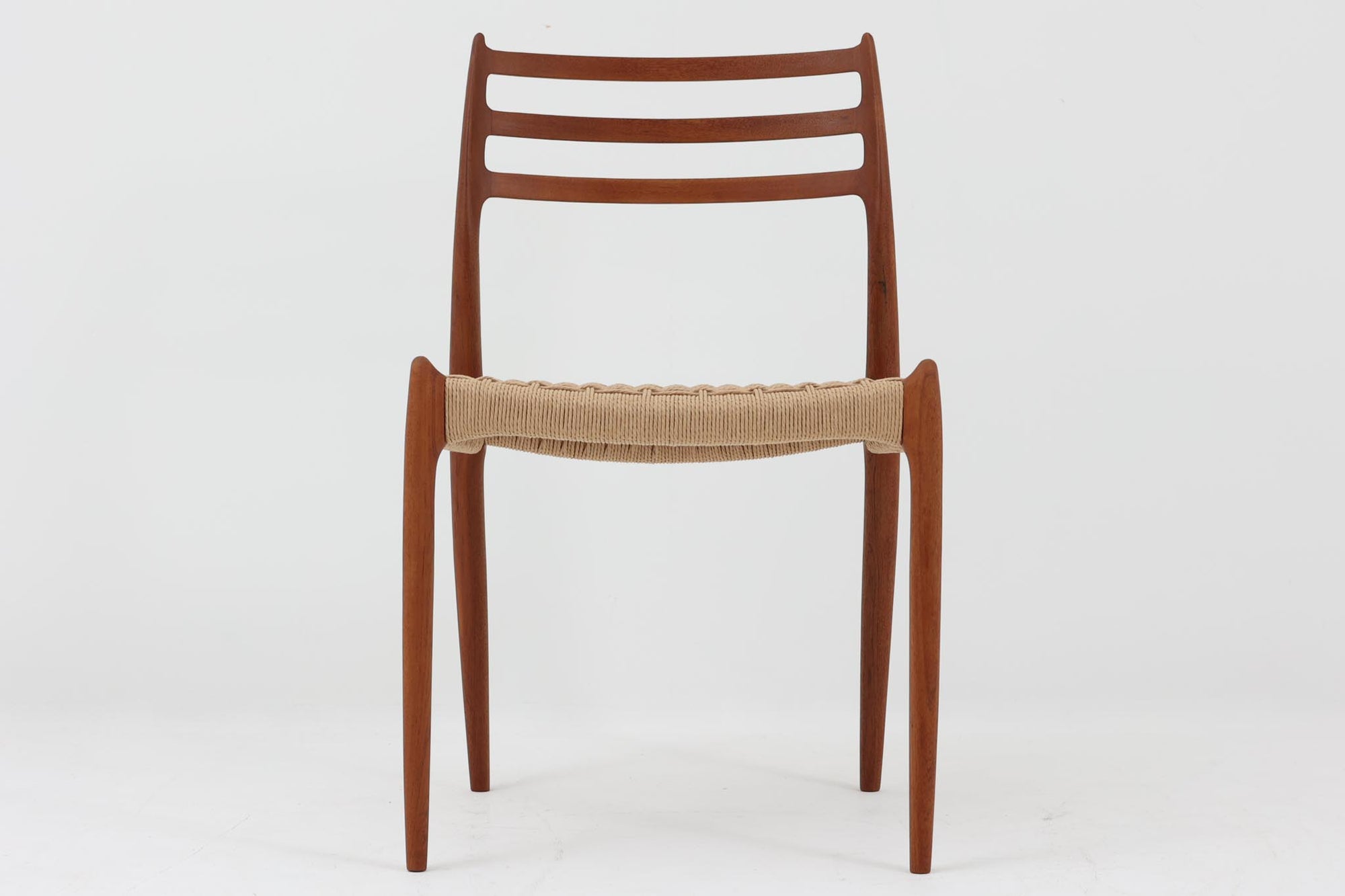 デンマークJ.L. moller社製のmodel 78チェアです。フレームには良質なチーク材が使用され、細いラインが組み合わさった工芸作品のような佇まいが魅力です。背もたれの美しいカーブや広めの座面により快適な座り心地を実現し、背もたれのラインは掃除の際に手を掛けやすく、使い勝手も優れています。座面には耐久性のあるペーパーコードを使用しており、張り替え済みのため清潔で快適にお使いいただけます。長く使用しても張替えが可能なため、世代を超えてご愛用いただけます。現行品でもチーク材モデルは販売されていますが、資材の入手が難しくなり、メーカー廃盤予定のため、今後はビンテージ品でのみ入手可能となる希少な一脚です。