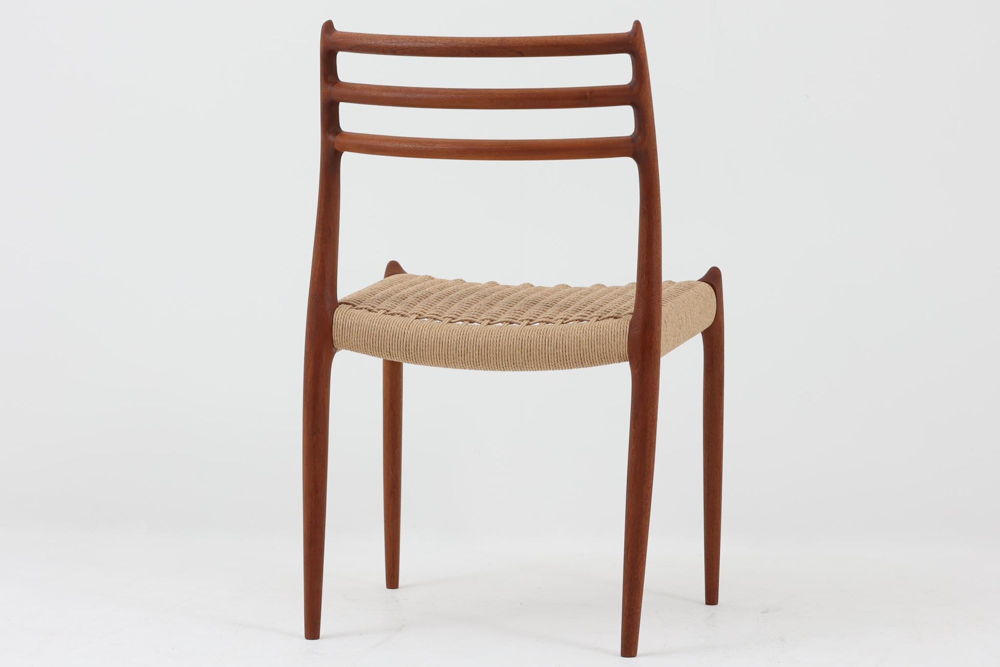 デンマークJ.L. moller社製のmodel 78チェアです。フレームには良質なチーク材が使用され、細いラインが組み合わさった工芸作品のような佇まいが魅力です。背もたれの美しいカーブや広めの座面により快適な座り心地を実現し、背もたれのラインは掃除の際に手を掛けやすく、使い勝手も優れています。座面には耐久性のあるペーパーコードを使用しており、張り替え済みのため清潔で快適にお使いいただけます。長く使用しても張替えが可能なため、世代を超えてご愛用いただけます。現行品でもチーク材モデルは販売されていますが、資材の入手が難しくなり、メーカー廃盤予定のため、今後はビンテージ品でのみ入手可能となる希少な一脚です。