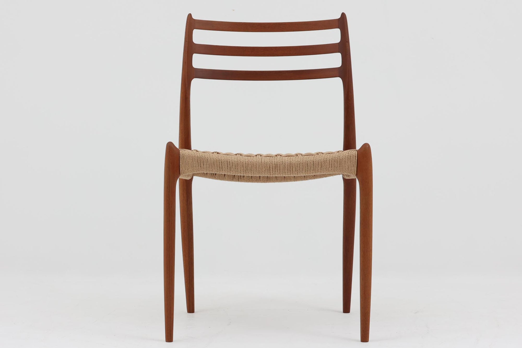 デンマークJ.L. moller社製のmodel 78チェアです。フレームには良質なチーク材が使用され、細いラインが組み合わさった工芸作品のような佇まいが魅力です。背もたれの美しいカーブや広めの座面により快適な座り心地を実現し、背もたれのラインは掃除の際に手を掛けやすく、使い勝手も優れています。座面には耐久性のあるペーパーコードを使用しており、張り替え済みのため清潔で快適にお使いいただけます。長く使用しても張替えが可能なため、世代を超えてご愛用いただけます。現行品でもチーク材モデルは販売されていますが、資材の入手が難しくなり、メーカー廃盤予定のため、今後はビンテージ品でのみ入手可能となる希少な一脚です。