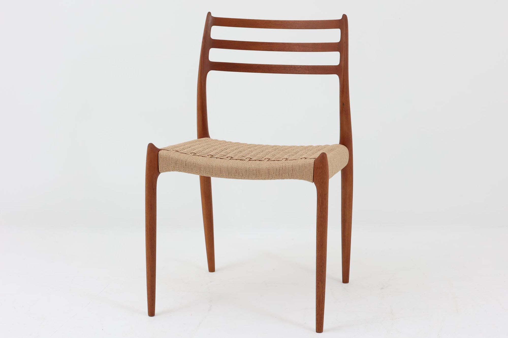 デンマークJ.L. moller社製のmodel 78チェアです。フレームには良質なチーク材が使用され、細いラインが組み合わさった工芸作品のような佇まいが魅力です。背もたれの美しいカーブや広めの座面により快適な座り心地を実現し、背もたれのラインは掃除の際に手を掛けやすく、使い勝手も優れています。座面には耐久性のあるペーパーコードを使用しており、張り替え済みのため清潔で快適にお使いいただけます。長く使用しても張替えが可能なため、世代を超えてご愛用いただけます。現行品でもチーク材モデルは販売されていますが、資材の入手が難しくなり、メーカー廃盤予定のため、今後はビンテージ品でのみ入手可能となる希少な一脚です。