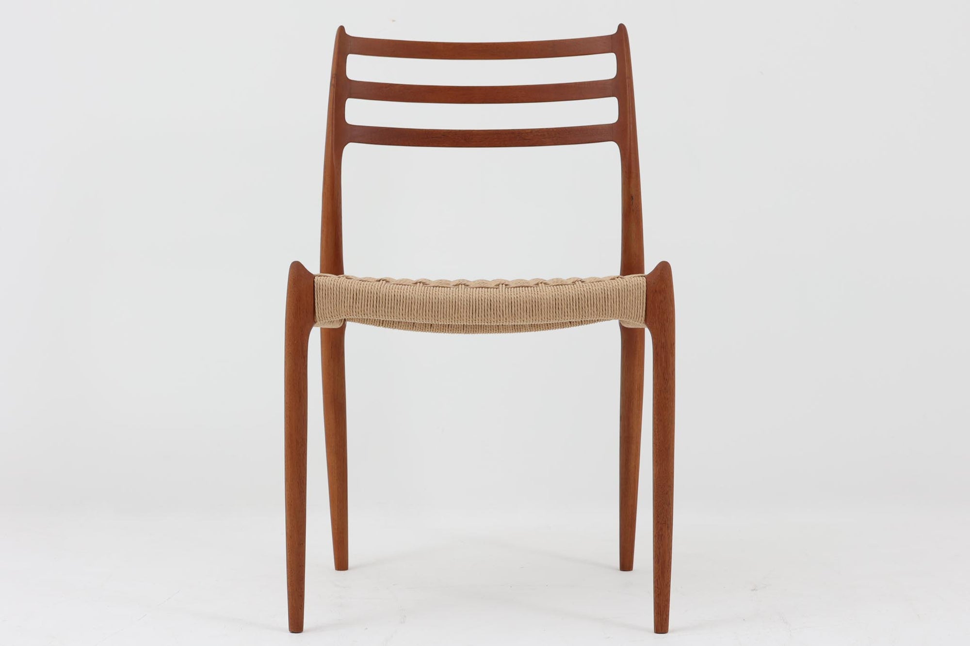 デンマークJ.L. moller社製のmodel 78チェアです。フレームには良質なチーク材が使用され、細いラインが組み合わさった工芸作品のような佇まいが魅力です。背もたれの美しいカーブや広めの座面により快適な座り心地を実現し、背もたれのラインは掃除の際に手を掛けやすく、使い勝手も優れています。座面には耐久性のあるペーパーコードを使用しており、張り替え済みのため清潔で快適にお使いいただけます。長く使用しても張替えが可能なため、世代を超えてご愛用いただけます。現行品でもチーク材モデルは販売されていますが、資材の入手が難しくなり、メーカー廃盤予定のため、今後はビンテージ品でのみ入手可能となる希少な一脚です。