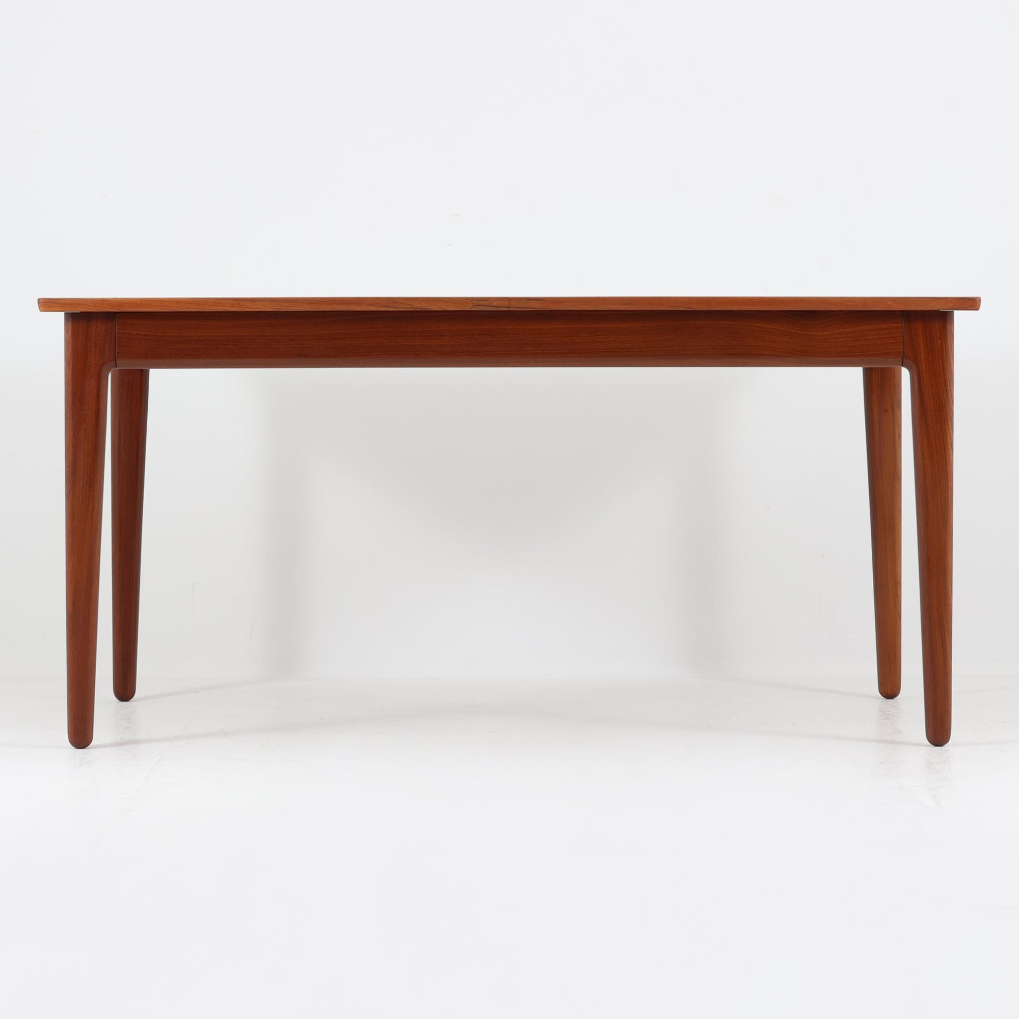 Vamo Mobelfabrikによって製造されたこちらのエクステンションダイニングテーブルは、チーク材の豊かな木目と重厚感のある質感が魅力の北欧ビンテージ家具で、幅150cmから最大270cmまで拡張可能な構造により、来客時や家族団らんの場にも柔軟に対応します。天板下に格納された2枚の中板を引き出して使用するシステムは実用性と美しさを兼ね備え、シャープなエッジと丸みを帯びた脚部が洗練された佇まいを演出します。デザイナー不明ながら、Vamo社ならではの確かな造りとDanish Controlラベルが品質の高さを物語る一台です。