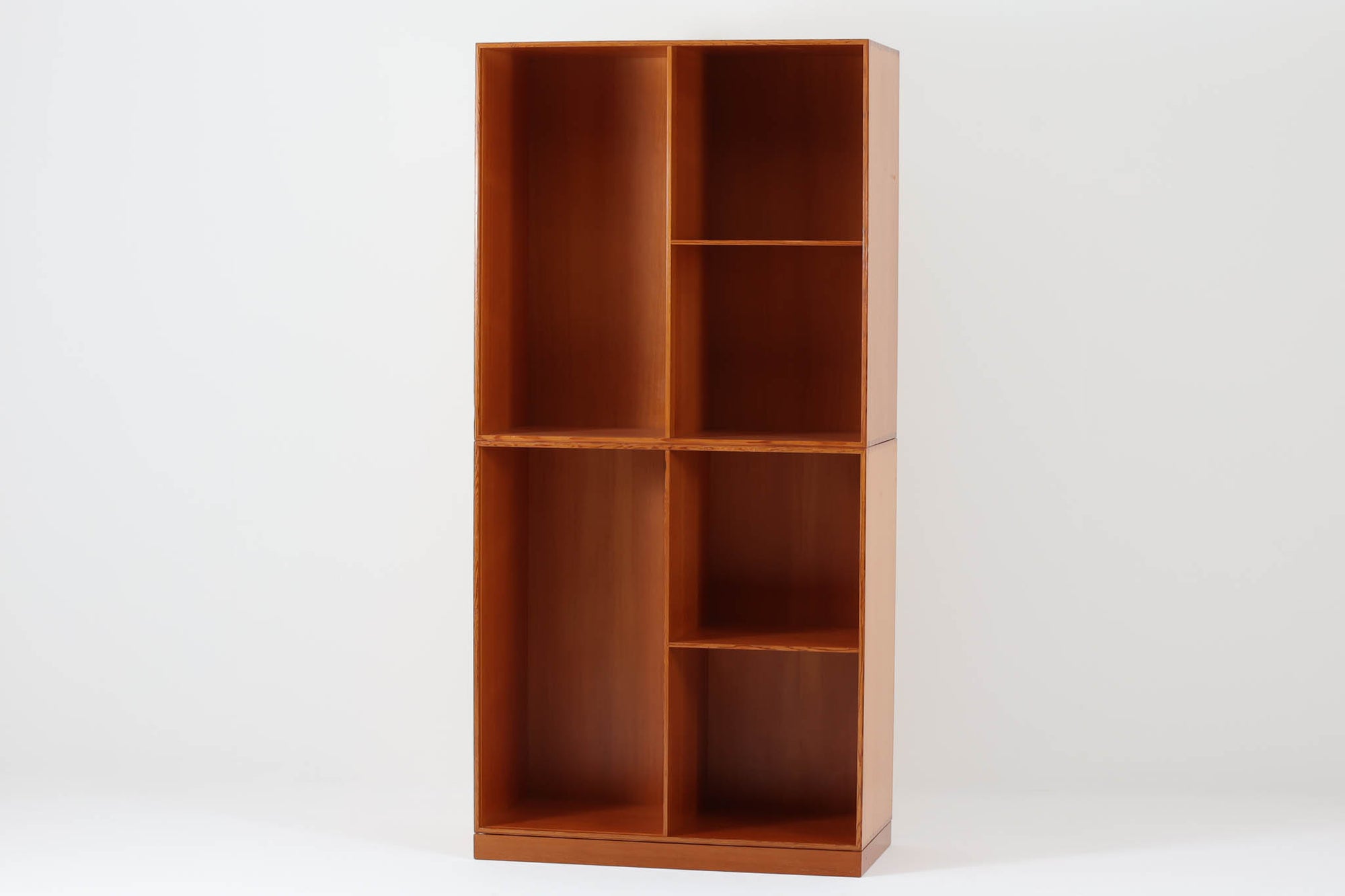 こちらは、1928年にmogens Kochによってデザインされた家具です。この家具には合板ではなく無垢材が使用されており、割れや狂いを防ぐためにさまざまな工夫が施されています。使用されているのは、良質で狂いが少ないパイン材の中でも、特に耐久性と強度に優れたオレゴンパインの無垢材が使用されています。経年変化によって深みを増した色味が魅力的な一点となっています。もともとは書斎用にデザインされたもので、扉付きキャビネットや奥行きの浅い棚など、好みに応じて組み合わせて使用できるシステムシェルフとして設計されています。そのため、ヴィンテージ家具市場では多様な組み合わせの形で見られることが特徴です。こちらの商品は、シンプルな台輪とシェルフ2点を組み合わせた構成となっています。