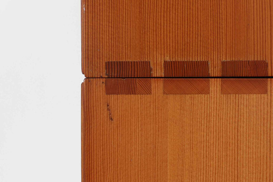 こちらは、1928年にmogens Kochによってデザインされた家具です。この家具には合板ではなく無垢材が使用されており、割れや狂いを防ぐためにさまざまな工夫が施されています。使用されているのは、良質で狂いが少ないパイン材の中でも、特に耐久性と強度に優れたオレゴンパインの無垢材が使用されています。経年変化によって深みを増した色味が魅力的な一点となっています。もともとは書斎用にデザインされたもので、扉付きキャビネットや奥行きの浅い棚など、好みに応じて組み合わせて使用できるシステムシェルフとして設計されています。そのため、ヴィンテージ家具市場では多様な組み合わせの形で見られることが特徴です。こちらの商品は、シンプルな台輪とシェルフ2点を組み合わせた構成となっています。