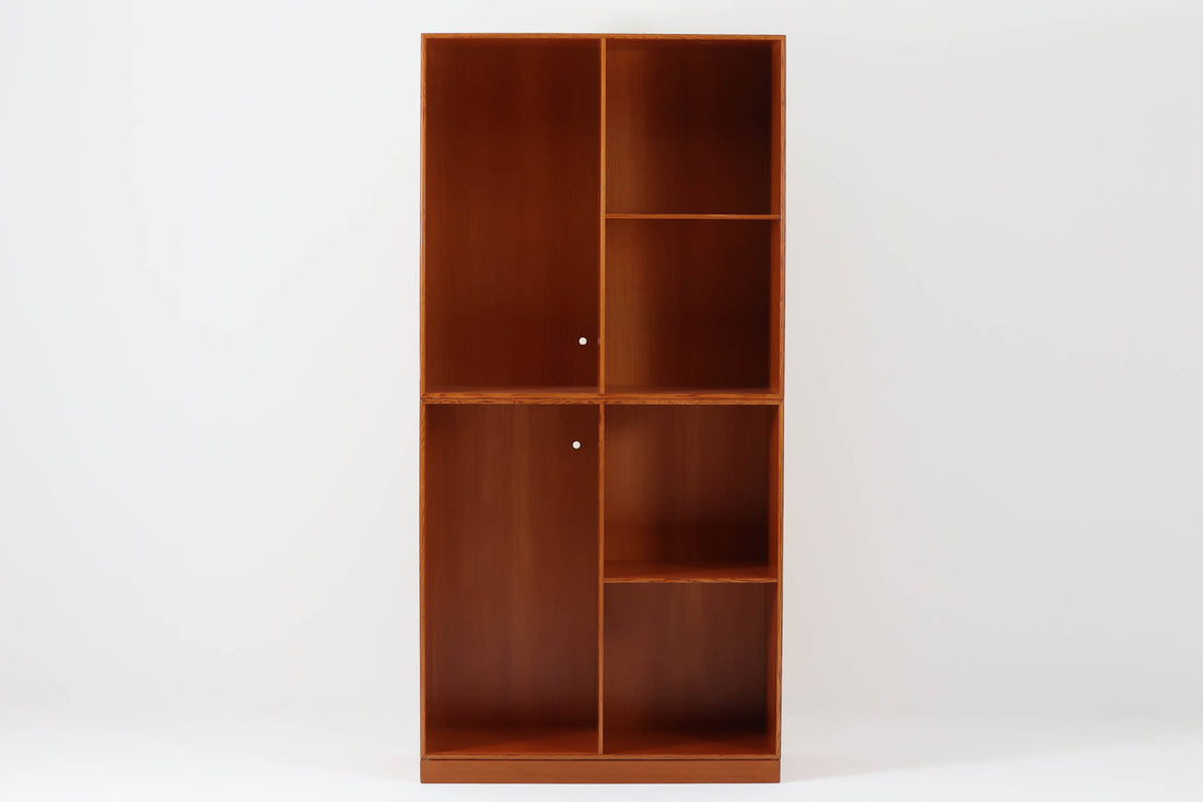 こちらは、1928年にmogens Kochによってデザインされた家具です。この家具には合板ではなく無垢材が使用されており、割れや狂いを防ぐためにさまざまな工夫が施されています。使用されているのは、良質で狂いが少ないパイン材の中でも、特に耐久性と強度に優れたオレゴンパインの無垢材が使用されています。経年変化によって深みを増した色味が魅力的な一点となっています。もともとは書斎用にデザインされたもので、扉付きキャビネットや奥行きの浅い棚など、好みに応じて組み合わせて使用できるシステムシェルフとして設計されています。そのため、ヴィンテージ家具市場では多様な組み合わせの形で見られることが特徴です。こちらの商品は、シンプルな台輪とシェルフ2点を組み合わせた構成となっています。