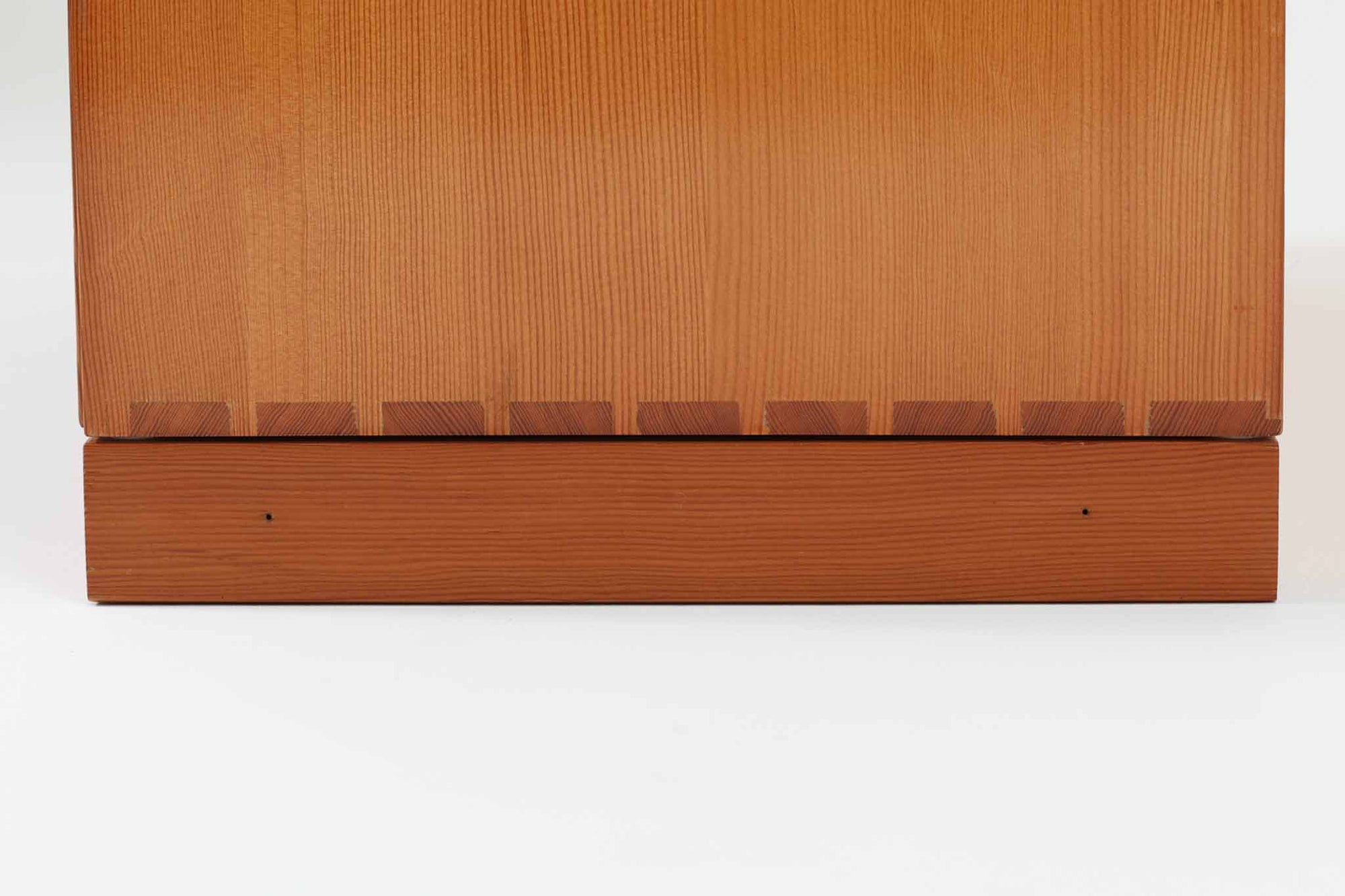 こちらは、1928年にmogens Kochによってデザインされた家具です。この家具には合板ではなく無垢材が使用されており、割れや狂いを防ぐためにさまざまな工夫が施されています。使用されているのは、良質で狂いが少ないパイン材の中でも、特に耐久性と強度に優れたオレゴンパインの無垢材が使用されています。経年変化によって深みを増した色味が魅力的な一点となっています。もともとは書斎用にデザインされたもので、扉付きキャビネットや奥行きの浅い棚など、好みに応じて組み合わせて使用できるシステムシェルフとして設計されています。そのため、ヴィンテージ家具市場では多様な組み合わせの形で見られることが特徴です。こちらの商品は、シンプルな台輪とシェルフ2点を組み合わせた構成となっています。