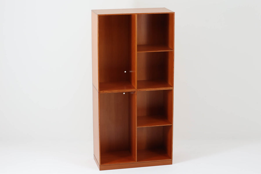 こちらは、1928年にmogens Kochによってデザインされた家具です。この家具には合板ではなく無垢材が使用されており、割れや狂いを防ぐためにさまざまな工夫が施されています。使用されているのは、良質で狂いが少ないパイン材の中でも、特に耐久性と強度に優れたオレゴンパインの無垢材が使用されています。経年変化によって深みを増した色味が魅力的な一点となっています。もともとは書斎用にデザインされたもので、扉付きキャビネットや奥行きの浅い棚など、好みに応じて組み合わせて使用できるシステムシェルフとして設計されています。そのため、ヴィンテージ家具市場では多様な組み合わせの形で見られることが特徴です。こちらの商品は、シンプルな台輪とシェルフ2点を組み合わせた構成となっています。