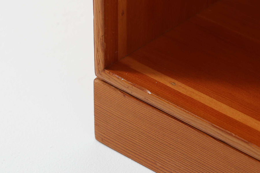 こちらは、1928年にmogens Kochによってデザインされた家具です。この家具には合板ではなく無垢材が使用されており、割れや狂いを防ぐためにさまざまな工夫が施されています。使用されているのは、良質で狂いが少ないパイン材の中でも、特に耐久性と強度に優れたオレゴンパインの無垢材が使用されています。経年変化によって深みを増した色味が魅力的な一点となっています。もともとは書斎用にデザインされたもので、扉付きキャビネットや奥行きの浅い棚など、好みに応じて組み合わせて使用できるシステムシェルフとして設計されています。そのため、ヴィンテージ家具市場では多様な組み合わせの形で見られることが特徴です。こちらの商品は、シンプルな台輪とシェルフ2点を組み合わせた構成となっています。