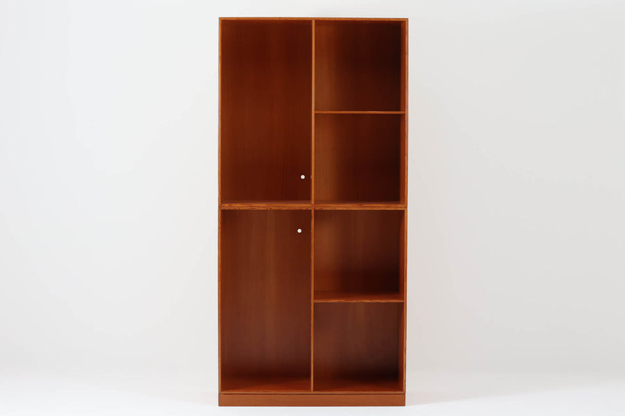 こちらは、1928年にmogens Kochによってデザインされた家具です。この家具には合板ではなく無垢材が使用されており、割れや狂いを防ぐためにさまざまな工夫が施されています。使用されているのは、良質で狂いが少ないパイン材の中でも、特に耐久性と強度に優れたオレゴンパインの無垢材が使用されています。経年変化によって深みを増した色味が魅力的な一点となっています。もともとは書斎用にデザインされたもので、扉付きキャビネットや奥行きの浅い棚など、好みに応じて組み合わせて使用できるシステムシェルフとして設計されています。そのため、ヴィンテージ家具市場では多様な組み合わせの形で見られることが特徴です。こちらの商品は、シンプルな台輪とシェルフ2点を組み合わせた構成となっています。