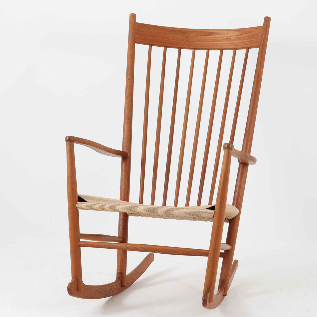 Hans J. Wegner（ハンス・J・ウェグナー）がデザインし、FDB Mobler社が製造したロッキングチェア「J16」。美しいチーク材のフレームとペーパーコードの座面が融合した、北欧ビンテージ家具を代表する一脚です。ハイバックと広めのアームが包み込むような座り心地を生み、ロッキングの揺れが心地よい安らぎをもたらします。経年により深みを増したチーク材の風合いが空間に静かな存在感を添え、読書やリラックスタイムに最適です。チーク材のモデルは希少で、現地デンマークのオークションで入手した確かな逸品です。